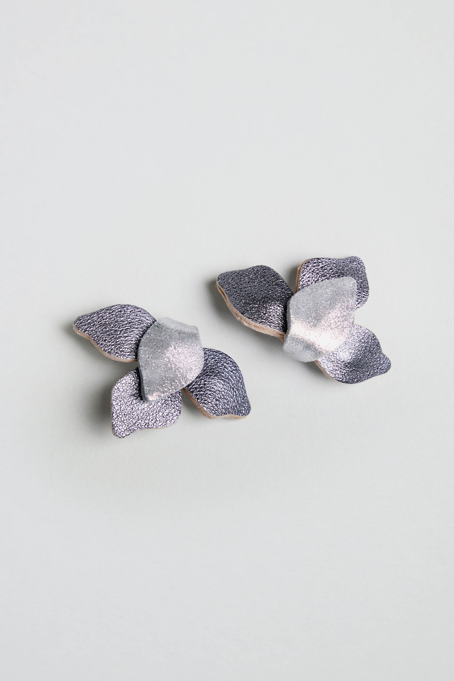 Metallic Grey Leather Petal Earrings in silver and lavender leather, shaped as abstract flowers, shown on a light grey background.