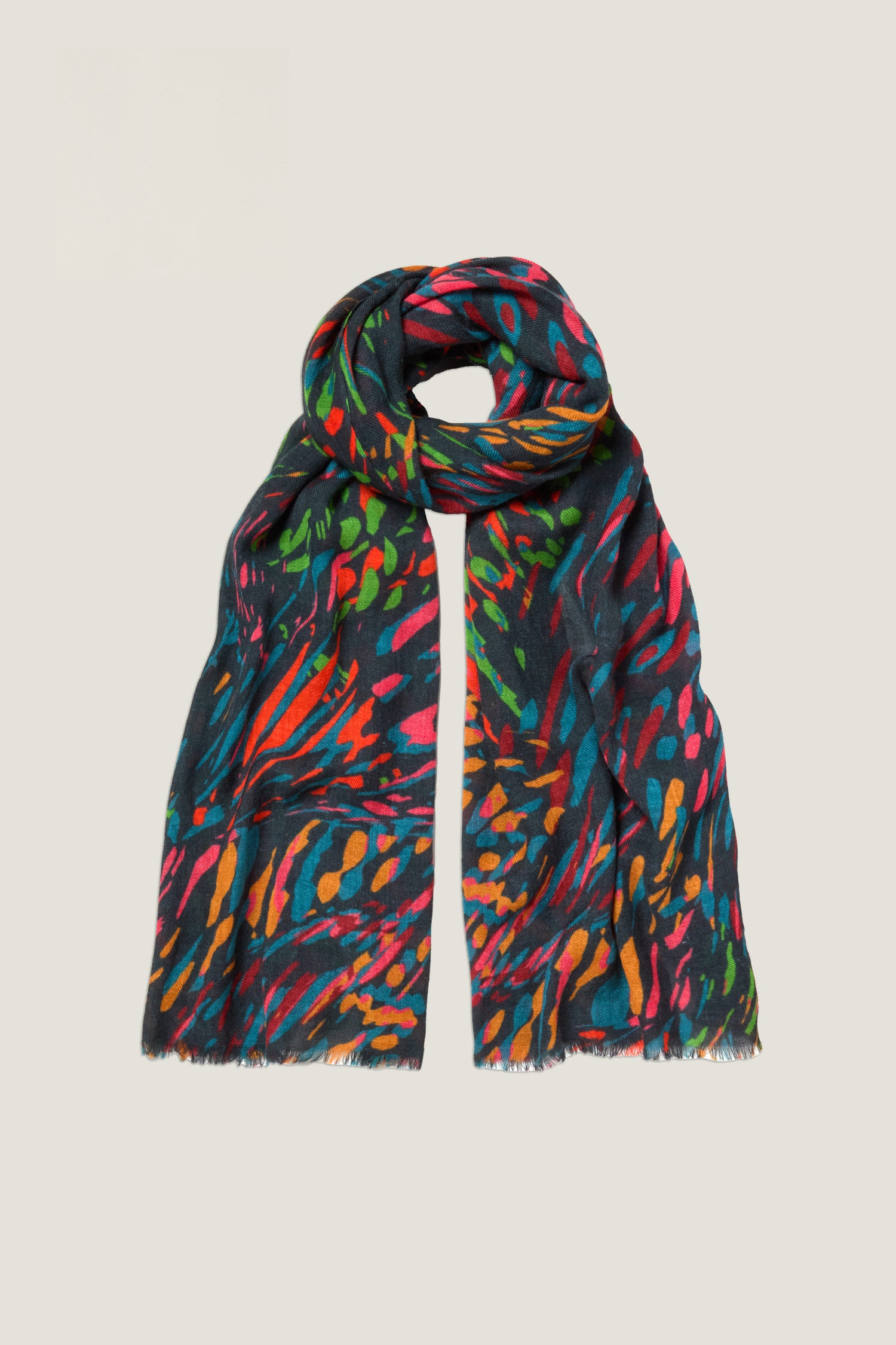 The Skyfire Scarf is a long, dark wool-silk scarf featuring a vibrant abstract pattern in red, green, blue, and orange, shown against a plain background.