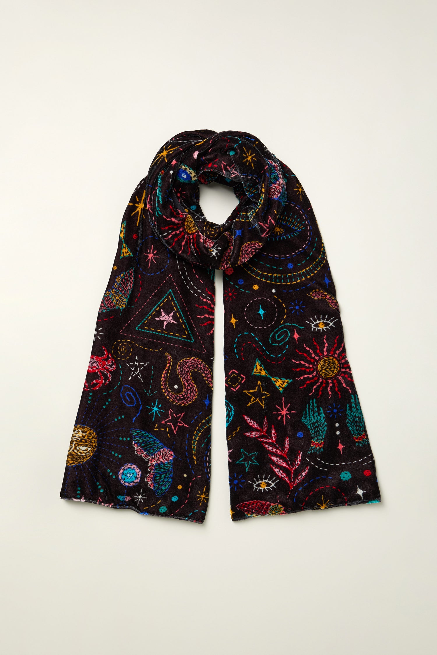 The Dream Stitched Print Scarf is a lightweight black scarf adorned with artisanal embroidery in colorful celestial and nature-inspired designs—stars, planets, and sea creatures—displayed flat on a light surface.