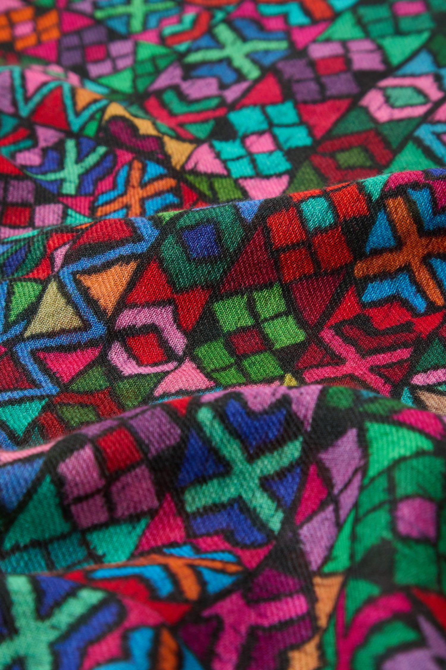 Close-up of colorful woven fabric with traditional Peruvian patterns in red, green, blue, pink, orange, and black—ideal for the Peruvian Stitched Print Scarf.