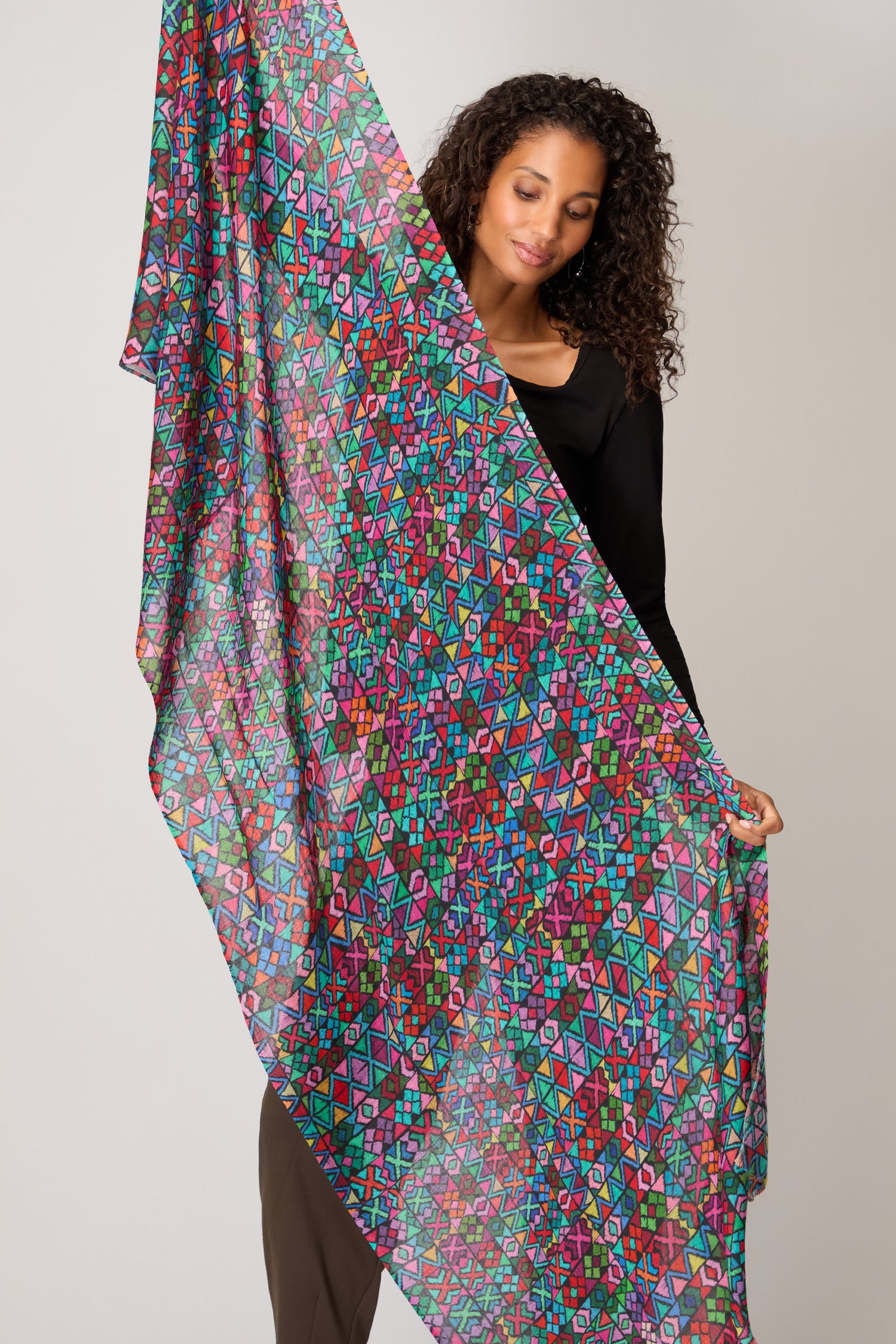 A woman showcases the Peruvian Stitched Print Scarf, a large and colorful fabric featuring traditional Peruvian patterns, perfect as a lightweight accessory against any backdrop.
