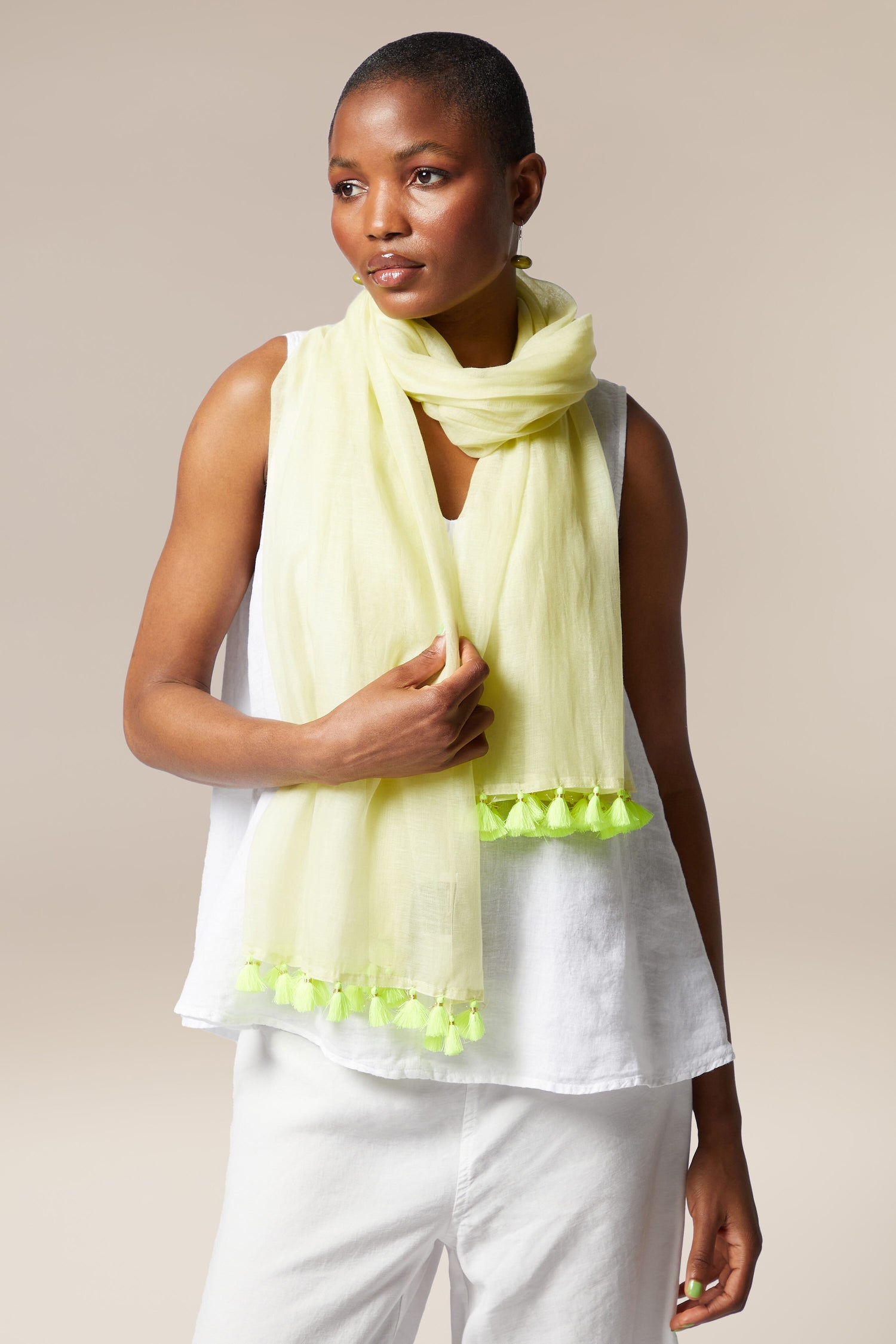 African American woman in a white outfit with a Neon Tassel Scarf, looking to the side, against a neutral background.