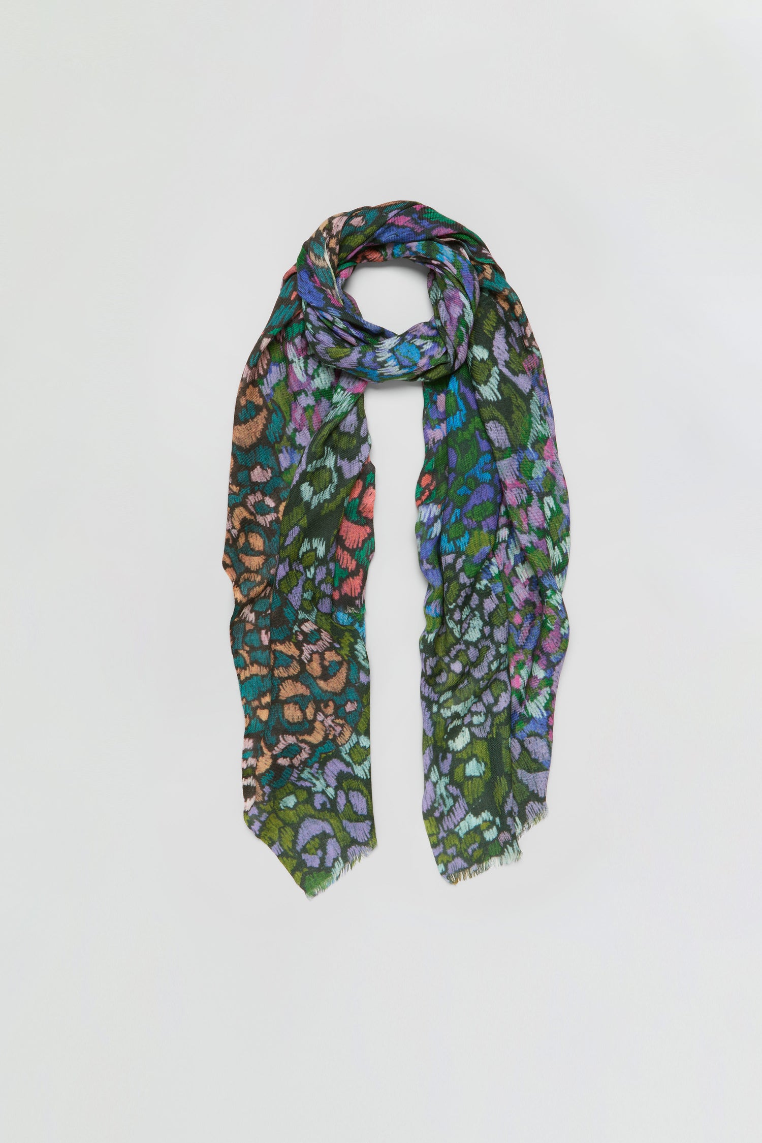 The Winter Garden Wool Scarf is a multicolored wool accessory with an abstract animal print in green, orange, purple, and blue hues, evoking the vibrancy of a winter garden and showcased against a simple light backdrop.