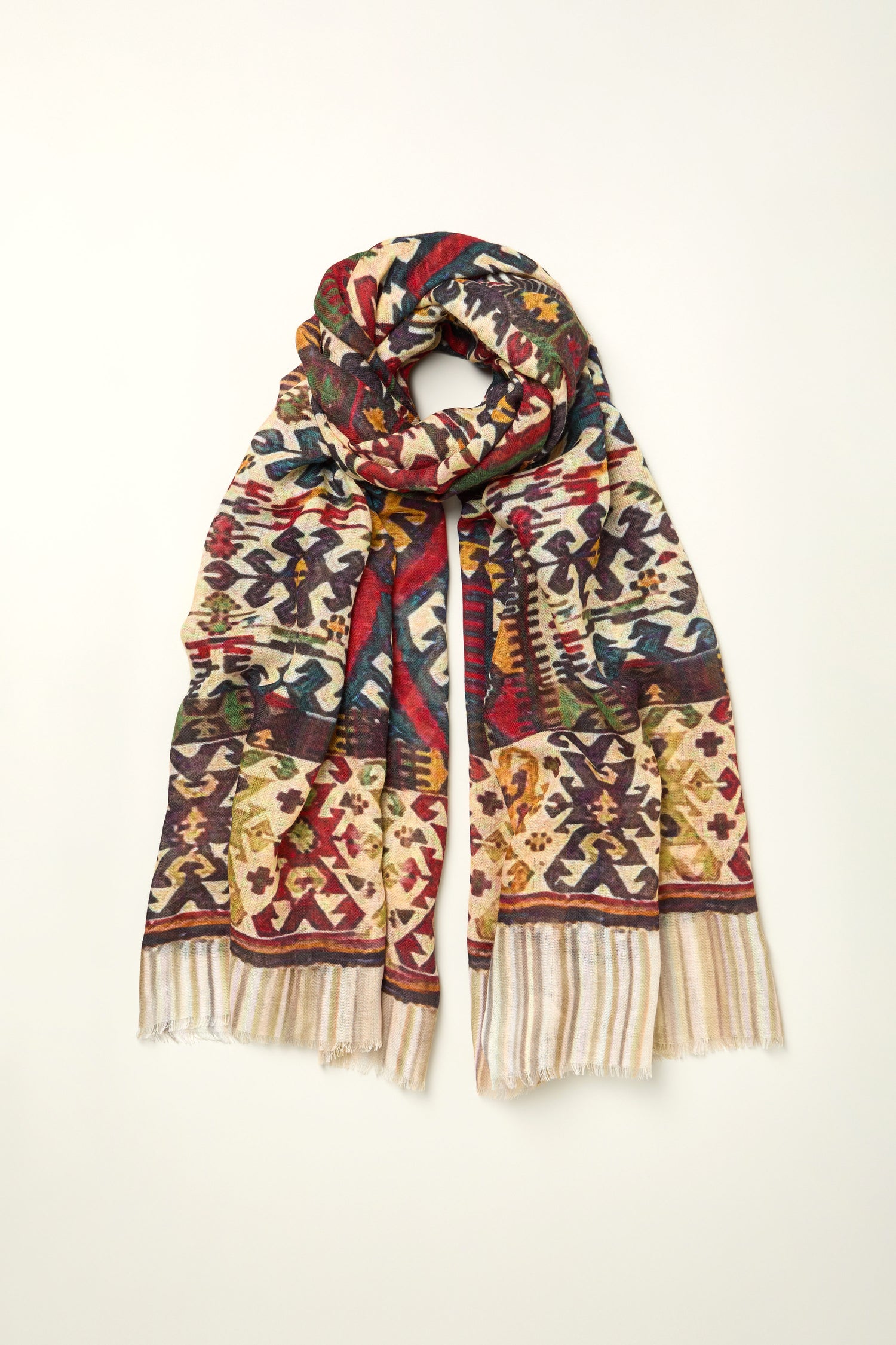 The Tapestry Wool Scarf, featuring a multicolored geometric and floral design with short fringe ends, is displayed flat on a neutral background.