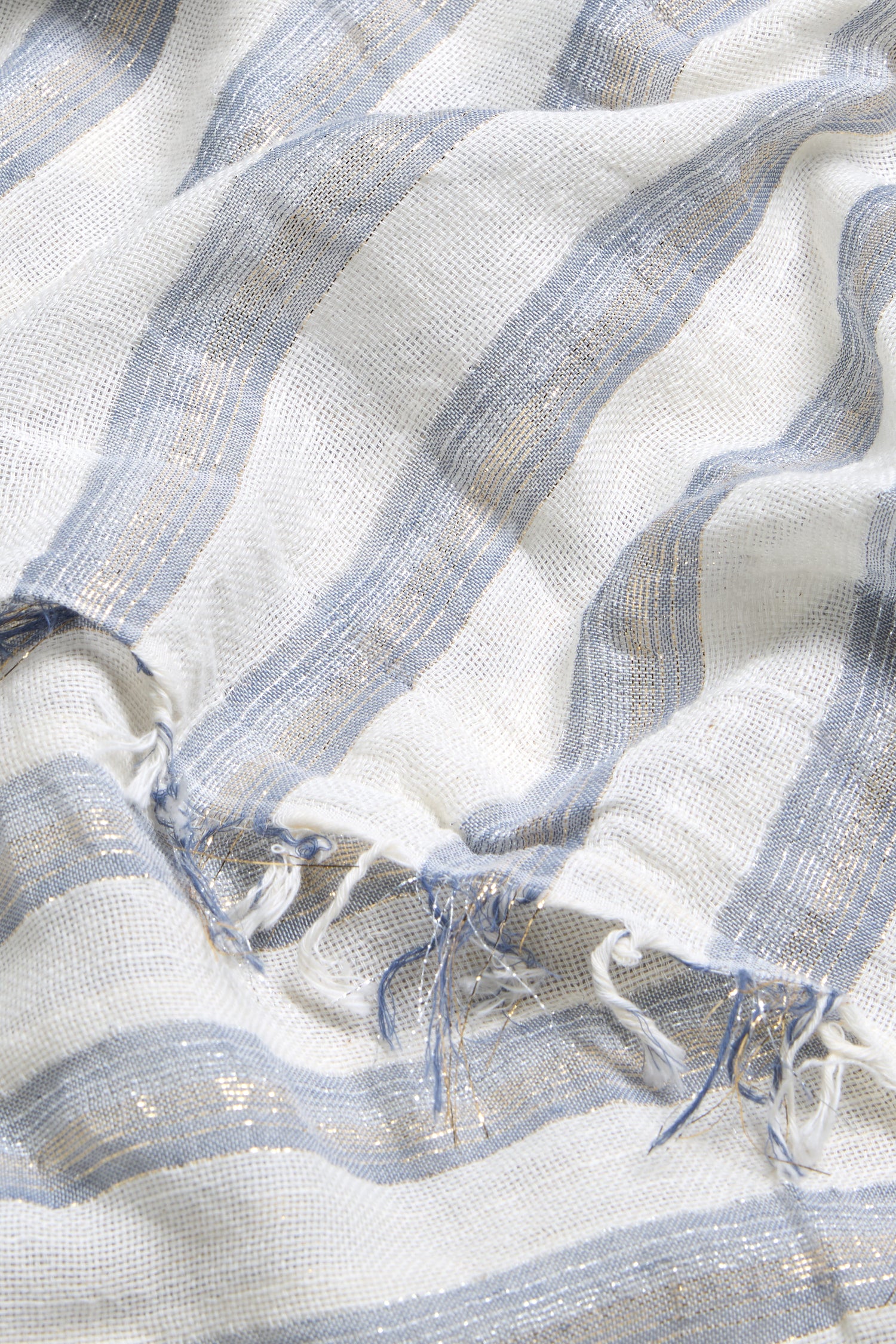 The Lurex Stripe Cotton Blend Scarf features white fabric with light blue and silver horizontal lurex stripes and frayed edges for added style.