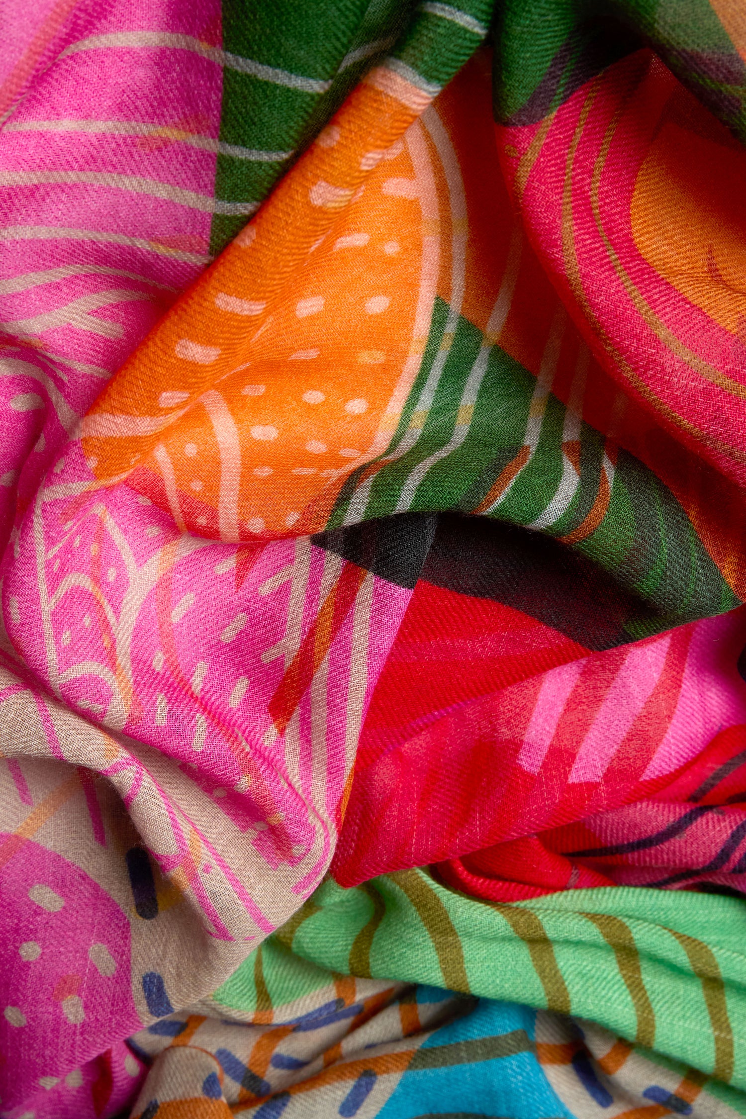 A close-up of the Tutti Frutti Wool Twill Scarf, featuring bright pink, orange, green, and beige abstract patterns with white dots, crafted from a luxurious wool and silk blend.