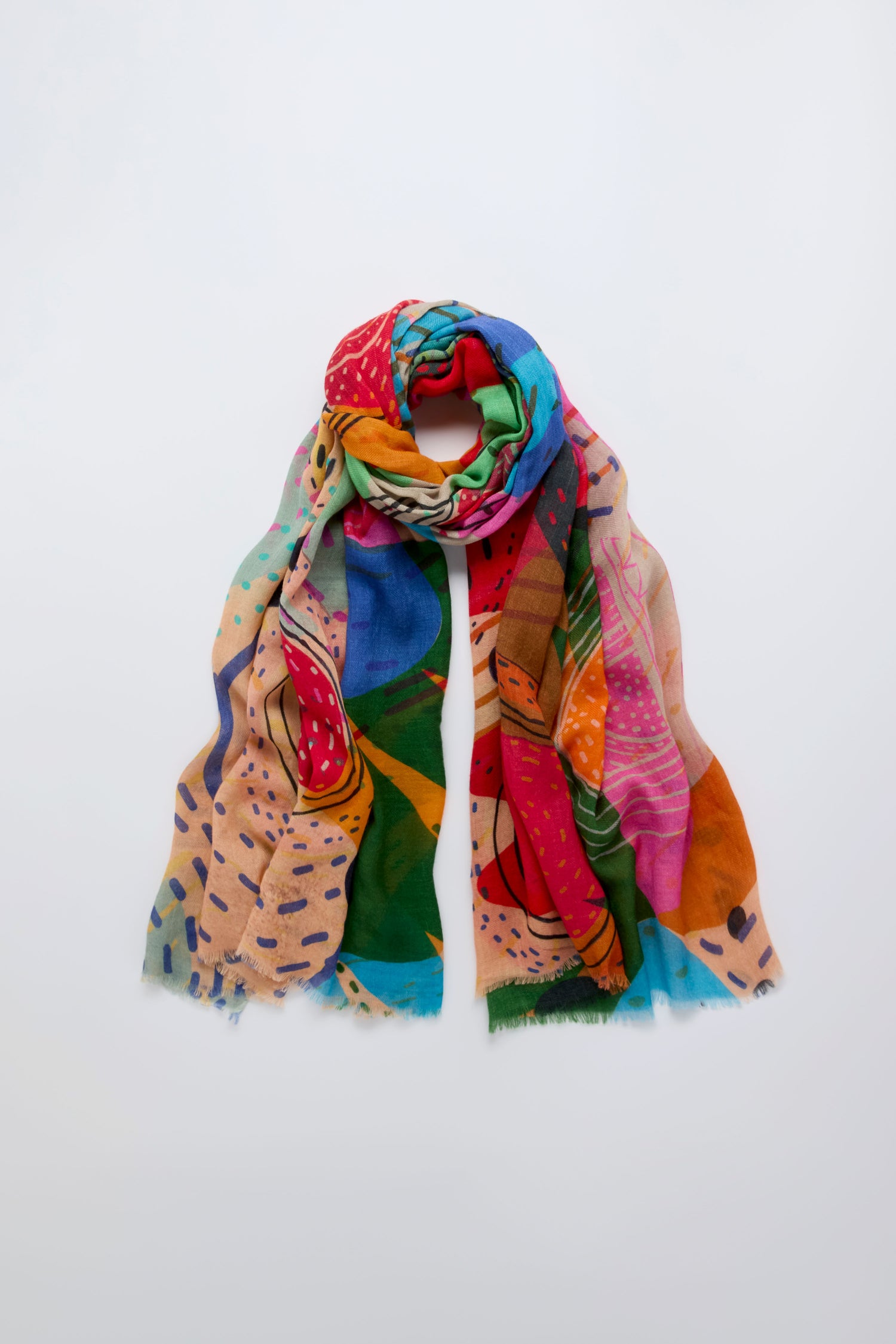 The Tutti Frutti Wool Twill Scarf, featuring a vibrant abstract pattern, is displayed flat and loosely rolled on a plain white background.