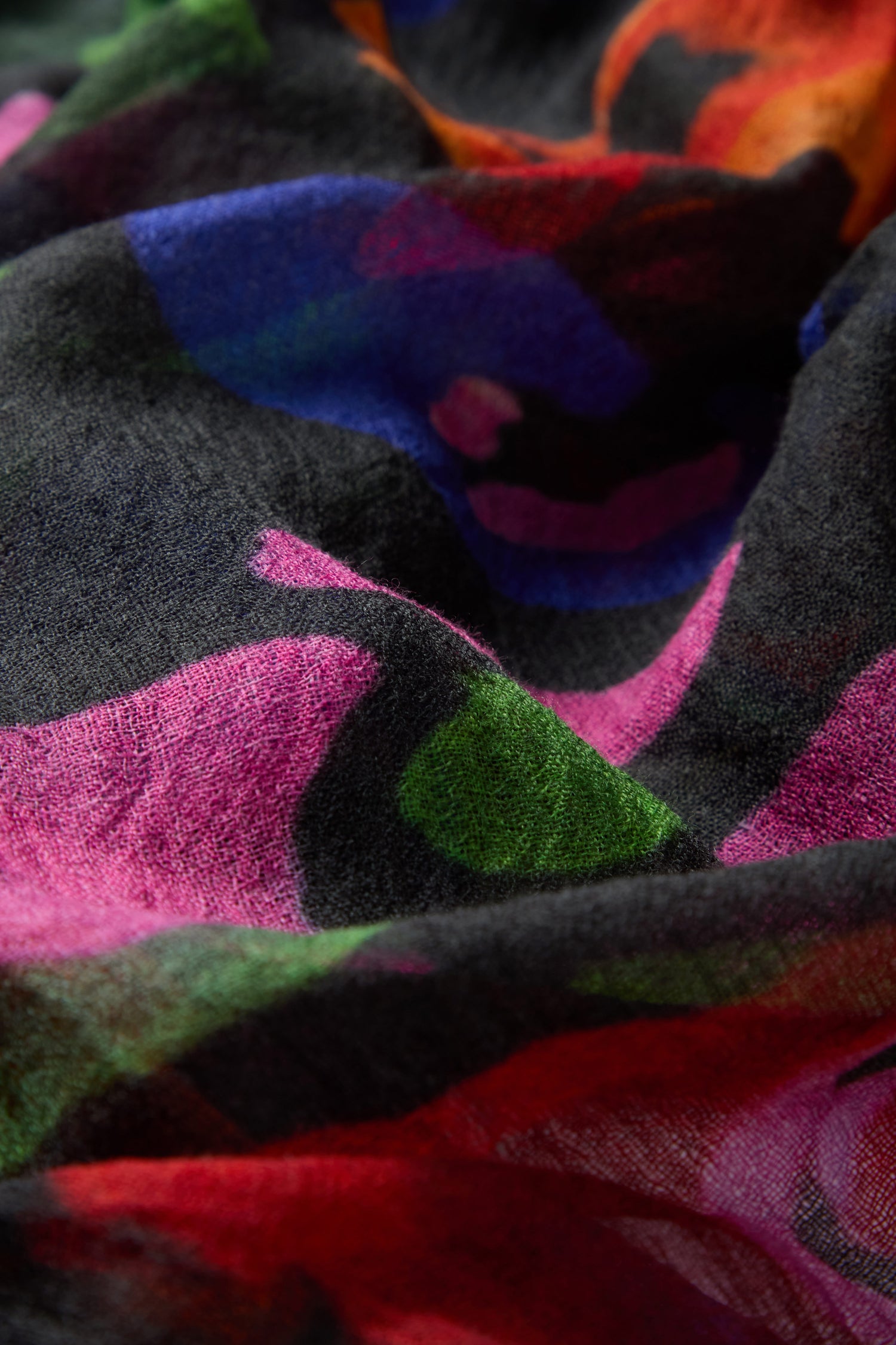 Close-up of the Painted Pansy Wool Scarf, showcasing abstract patterns in shades of pink, green, blue, orange, and black with a soft texture and gentle folds reminiscent of a painted pansy print.