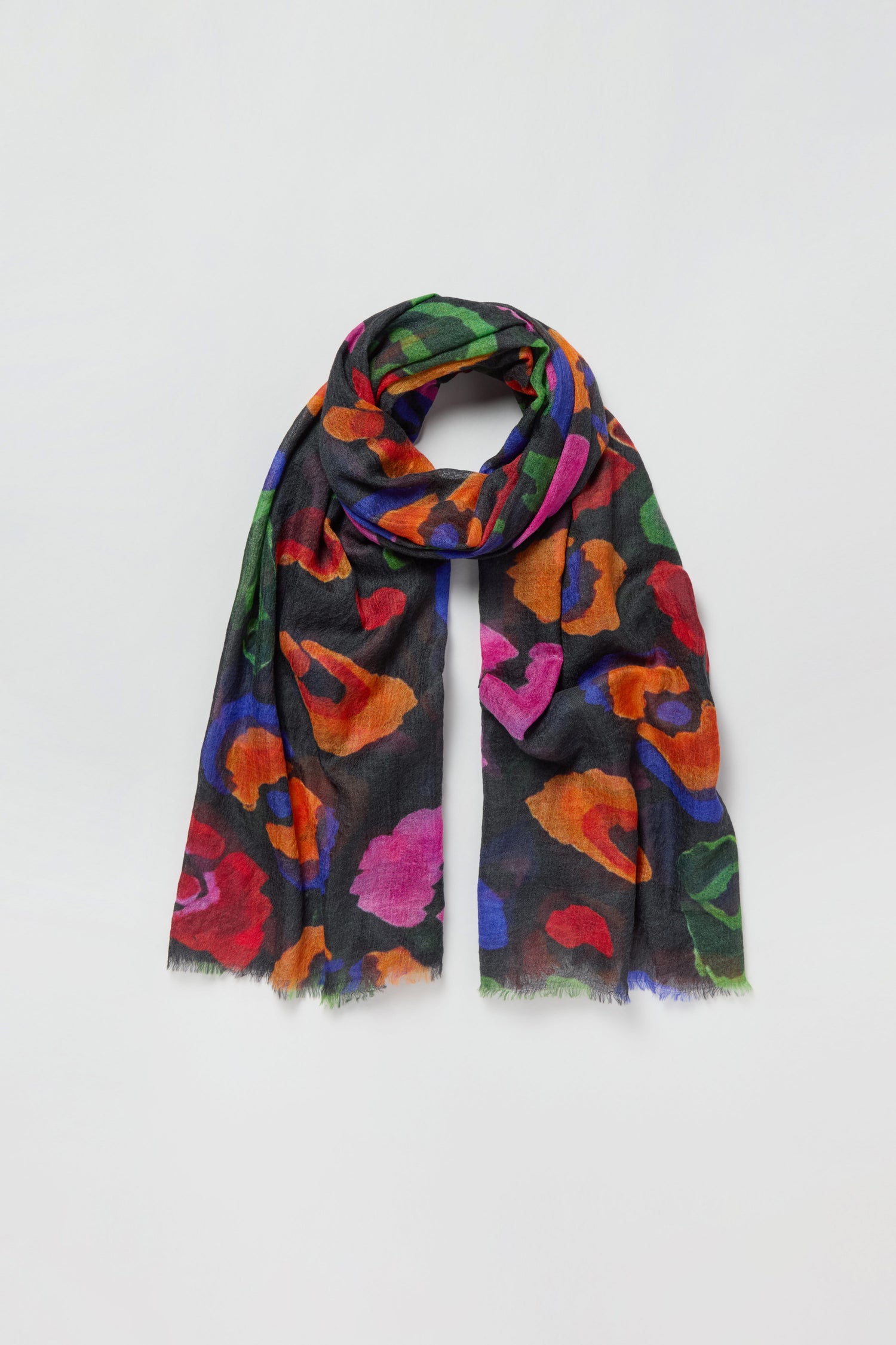 The Painted Pansy Wool Scarf is a black wool scarf adorned with vibrant floral patterns in red, orange, purple, and green, showcasing a bold painted pansy print. Displayed on a plain white background, this multicolour accessory is sure to brighten any outfit.
