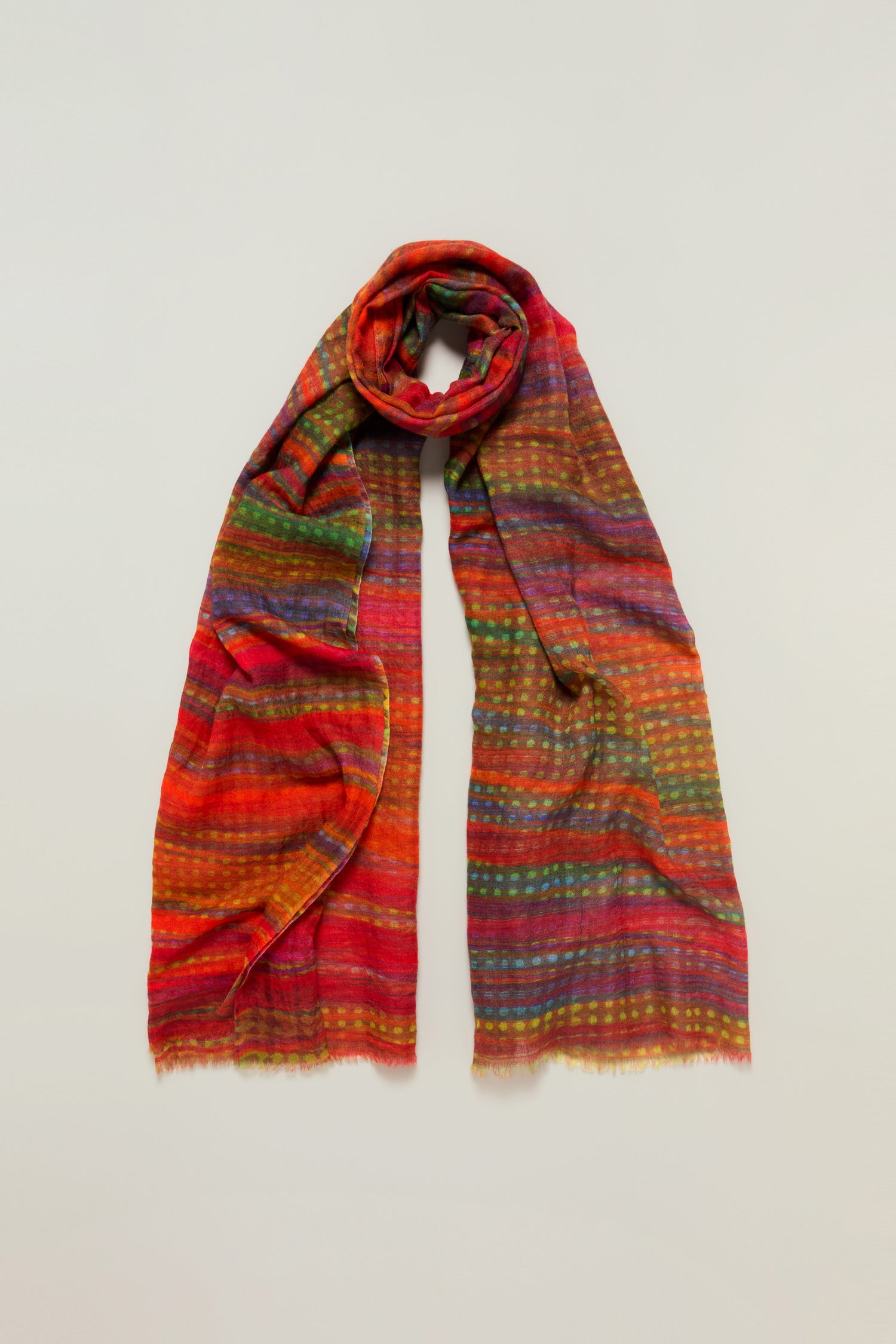 The Sundown Stripe Wool Scarf, featuring oversized dimensions and multicolored stripes in soft wool, is displayed on a plain, light background.