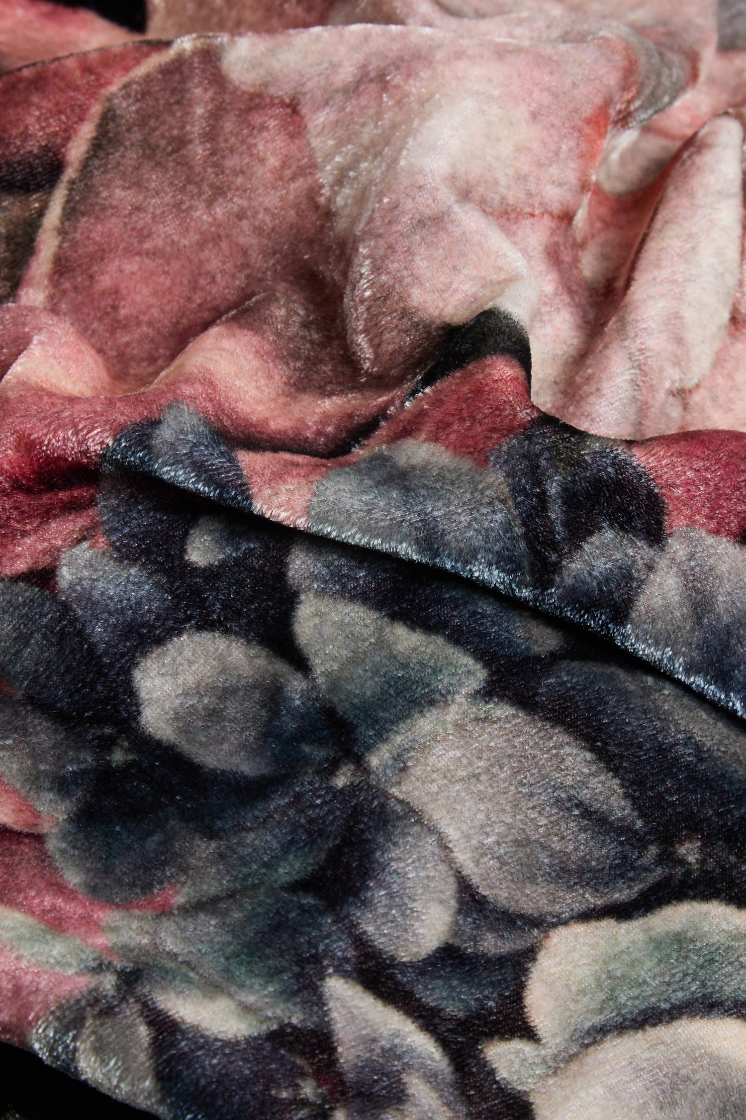 Close-up of the Winter Rose Velvet Scarf, featuring a soft, velvety fabric adorned with a winter rose print in muted shades of pink, purple, and gray. This luxurious scarf is crafted from a premium blend of modal, wool, and silk, showcasing elegant folds and an intricate floral pattern that highlights its sumptuous texture.