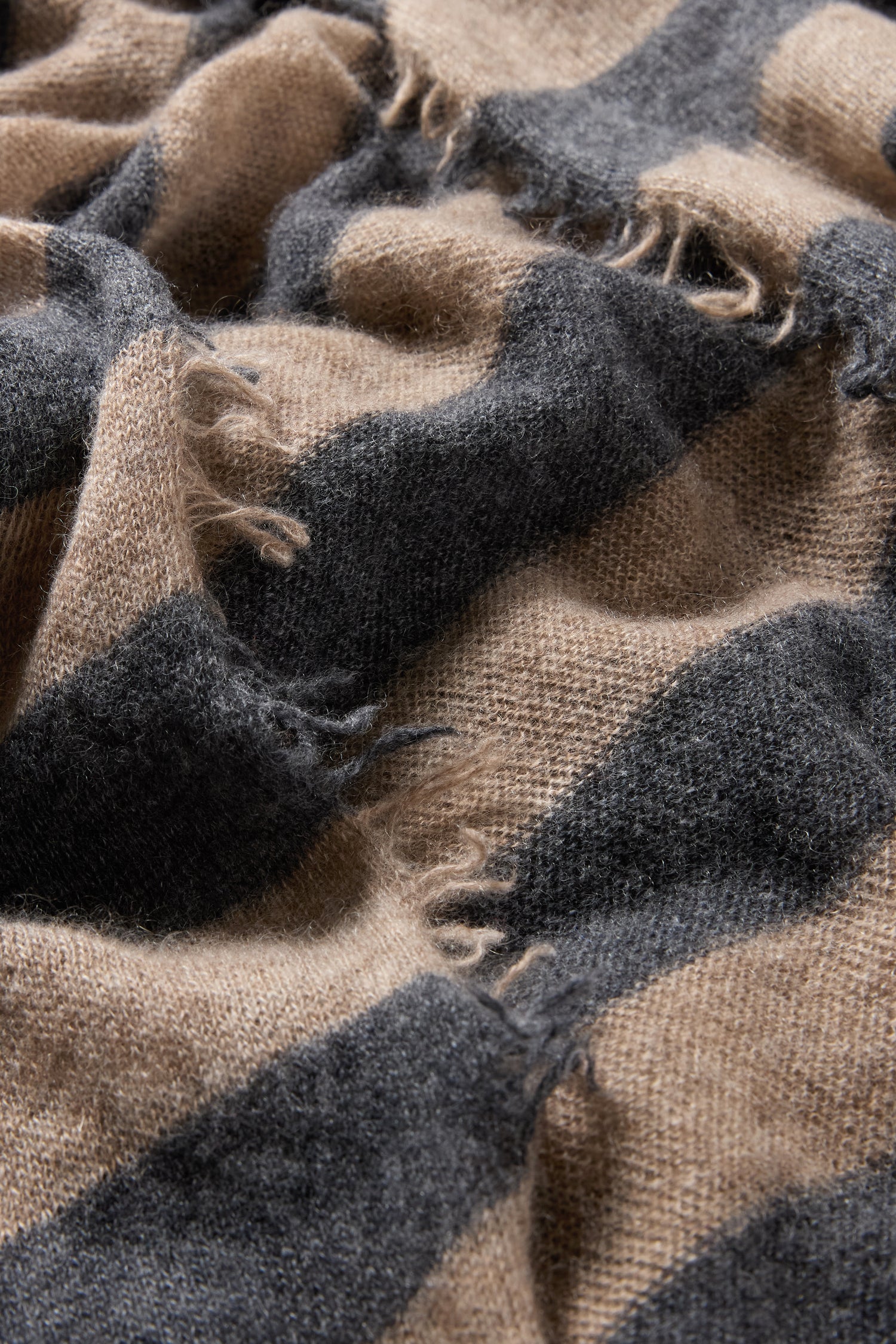 Close-up of the Soft Stripe Cashmere Scarf featuring wide black and tan stripes with frayed edges—an ideal accessory to elevate your winter wardrobe.