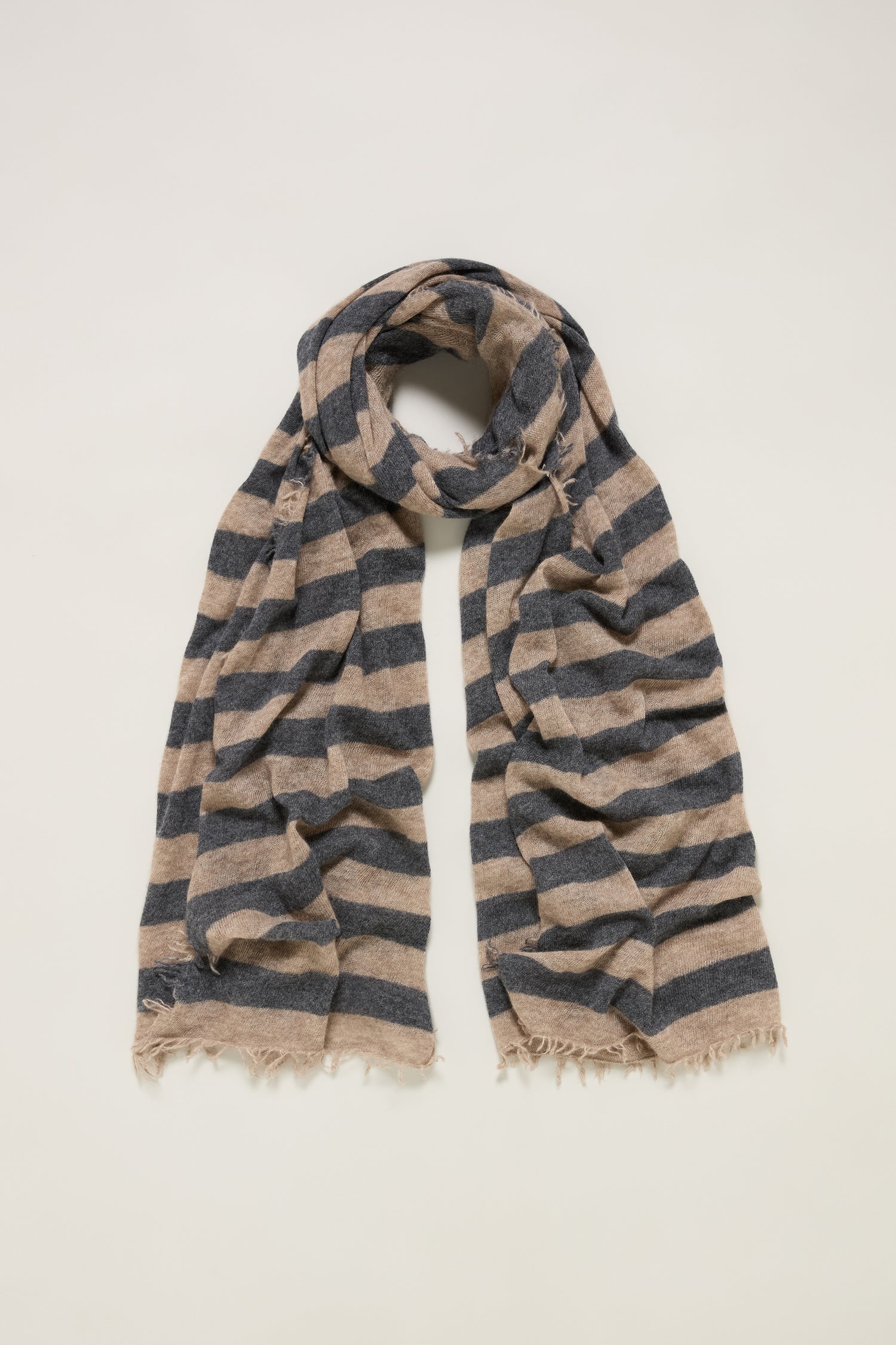 The Soft Stripe Cashmere Scarf features horizontal navy and beige stripes, frayed edges, and is loosely folded in a loop—a versatile winter essential, displayed on a plain background.