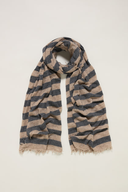 The Soft Stripe Cashmere Scarf features horizontal navy and beige stripes, frayed edges, and is loosely folded in a loop—a versatile winter essential, displayed on a plain background.