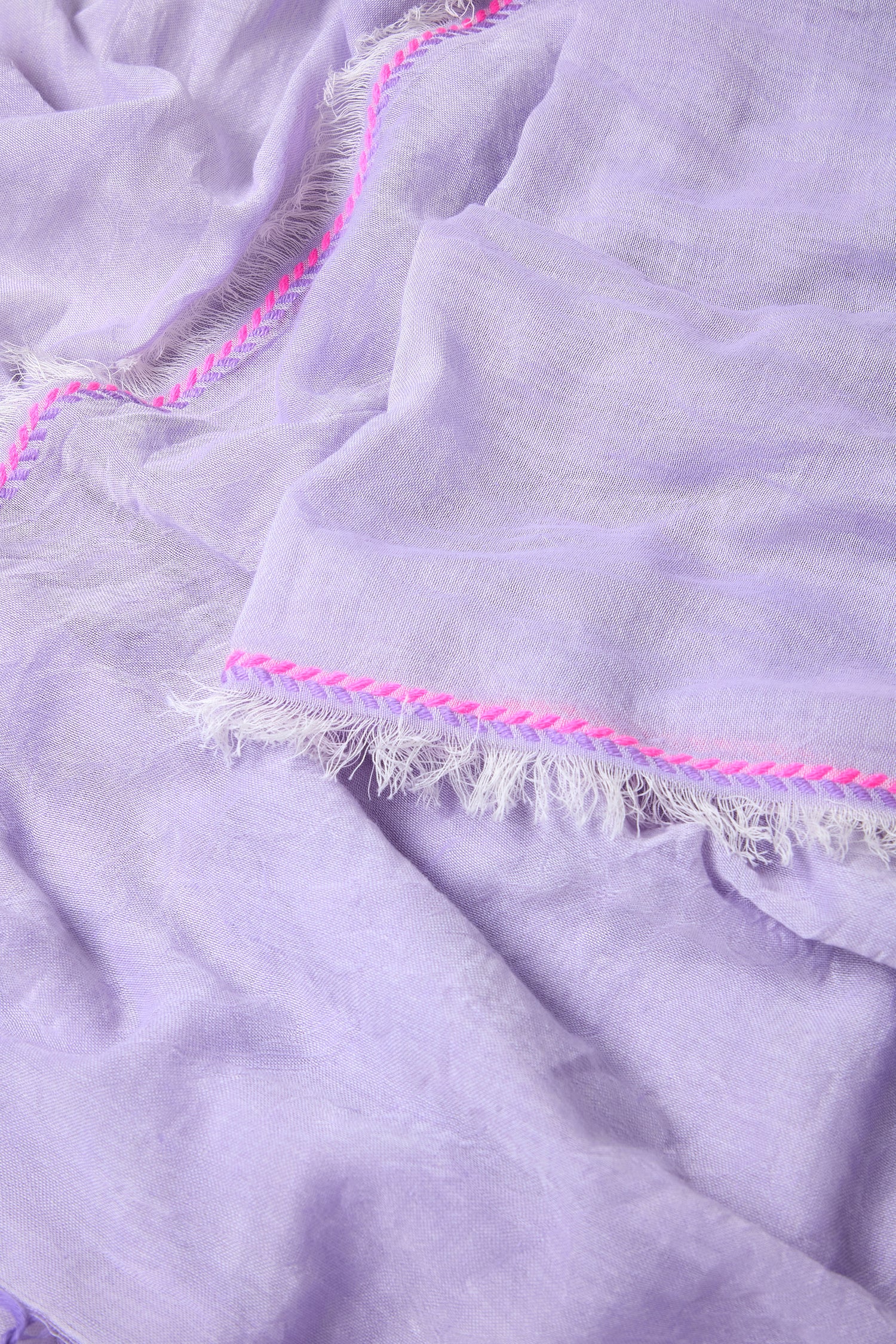 Close-up of the Lilac Fringe Cotton Scarf featuring frayed edges and a decorative pink stitched trim.