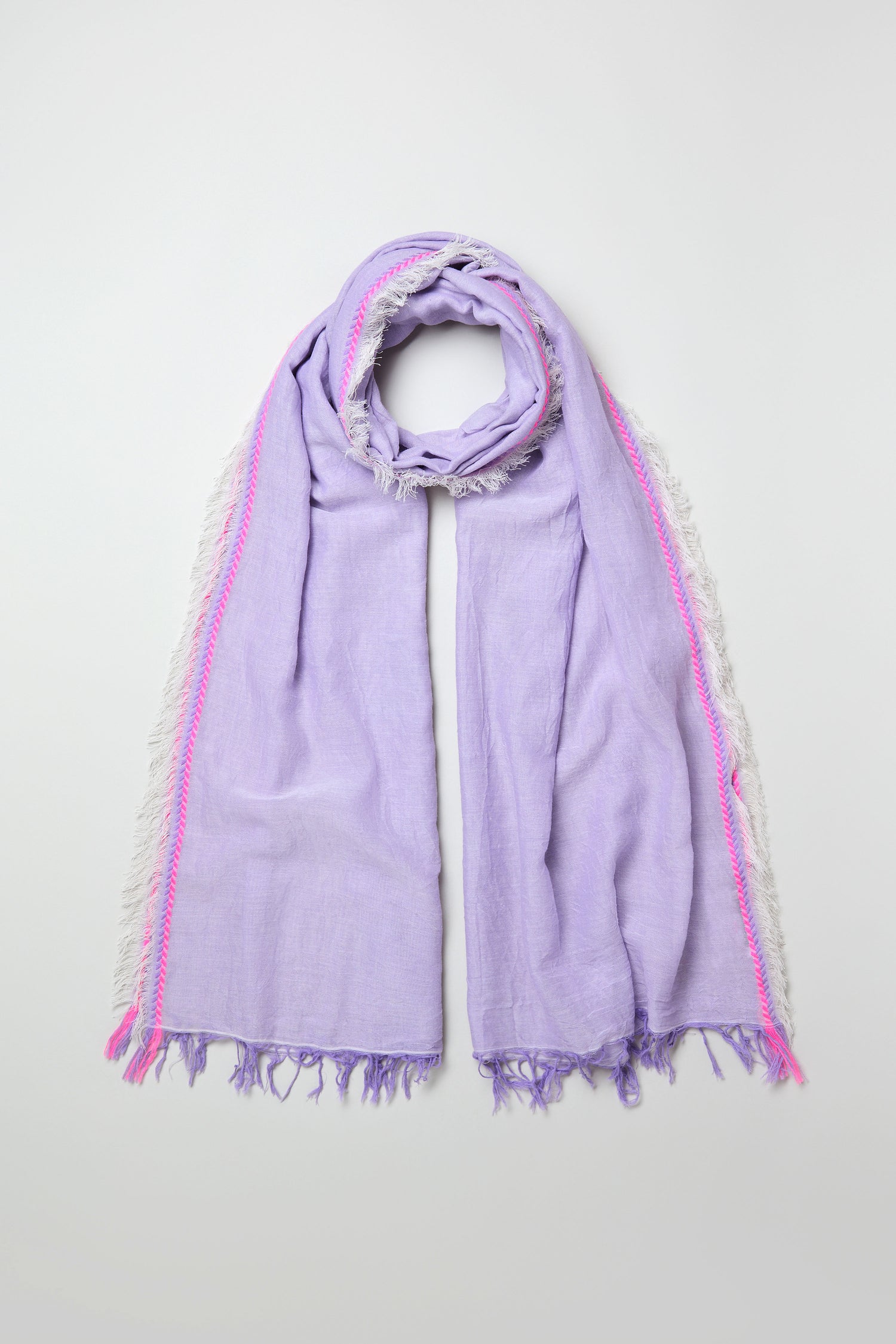 The Lilac Fringe Cotton Scarf, featuring a lightweight cotton fabric with white side fringe and pink accents, is laid flat on a plain light background.