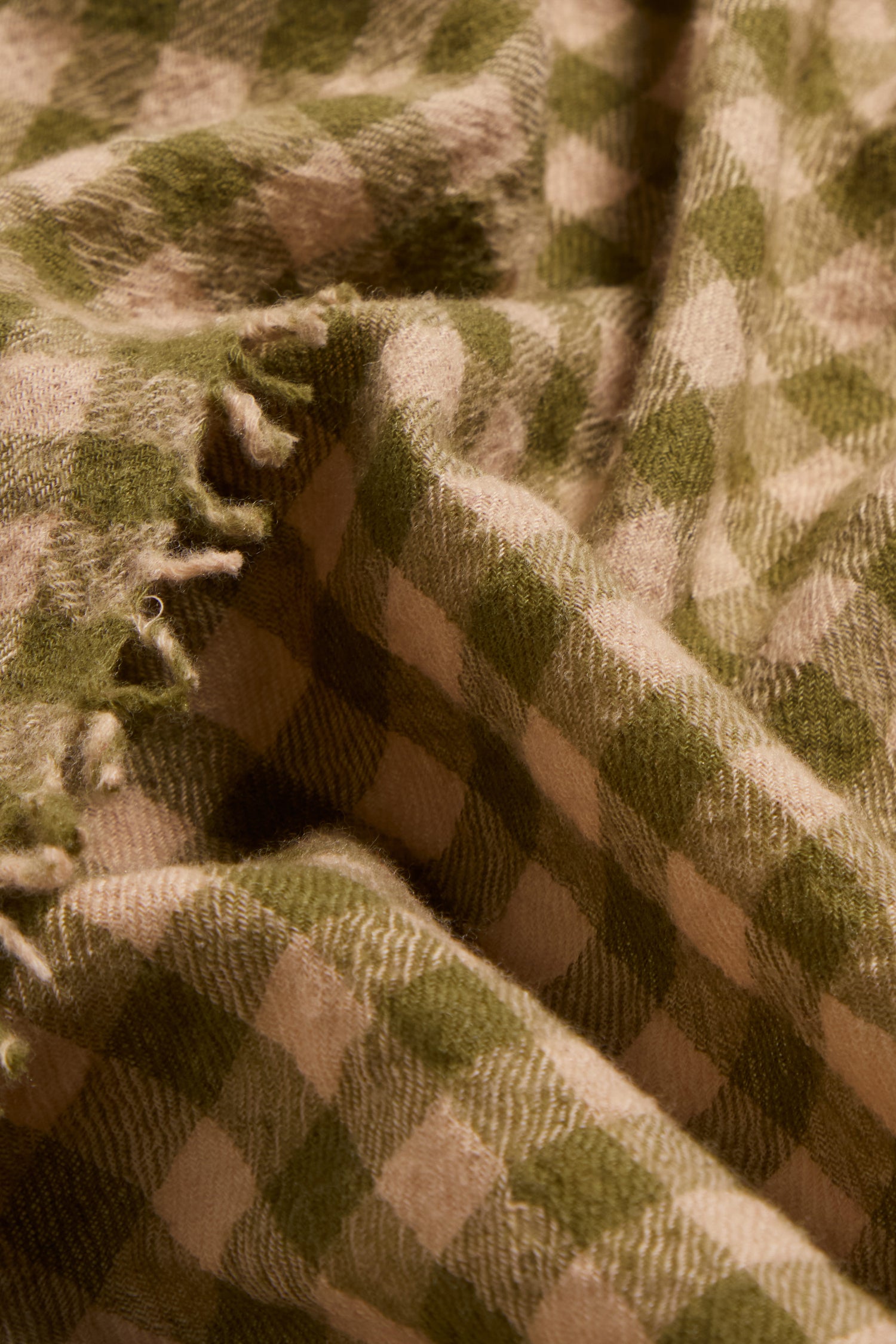 Close-up of the Boiled Wool Gingham Check Scarf showcasing its soft, textured feel, green and beige checked pattern, frayed edges, and lightweight warmth.
