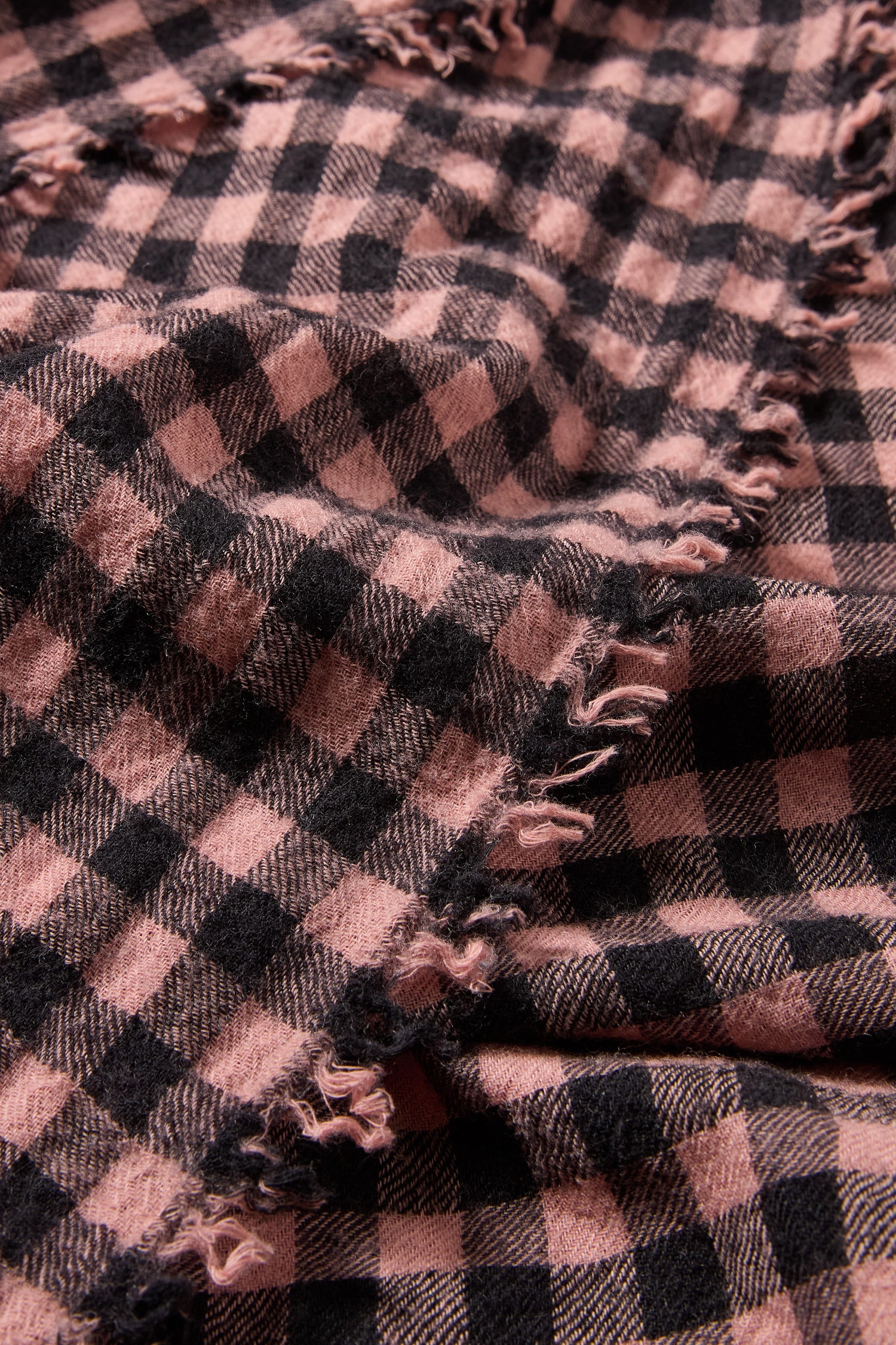 Close-up of the Boiled Wool Gingham Check Scarf in pink and black with frayed edges, showcasing its soft, textured surface—perfect for lightweight warmth.