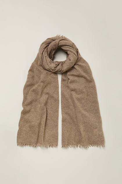 The Cashmere Sparkle Scarf, in light brown pure cashmere with frayed edges, is displayed flat on a simple neutral background.