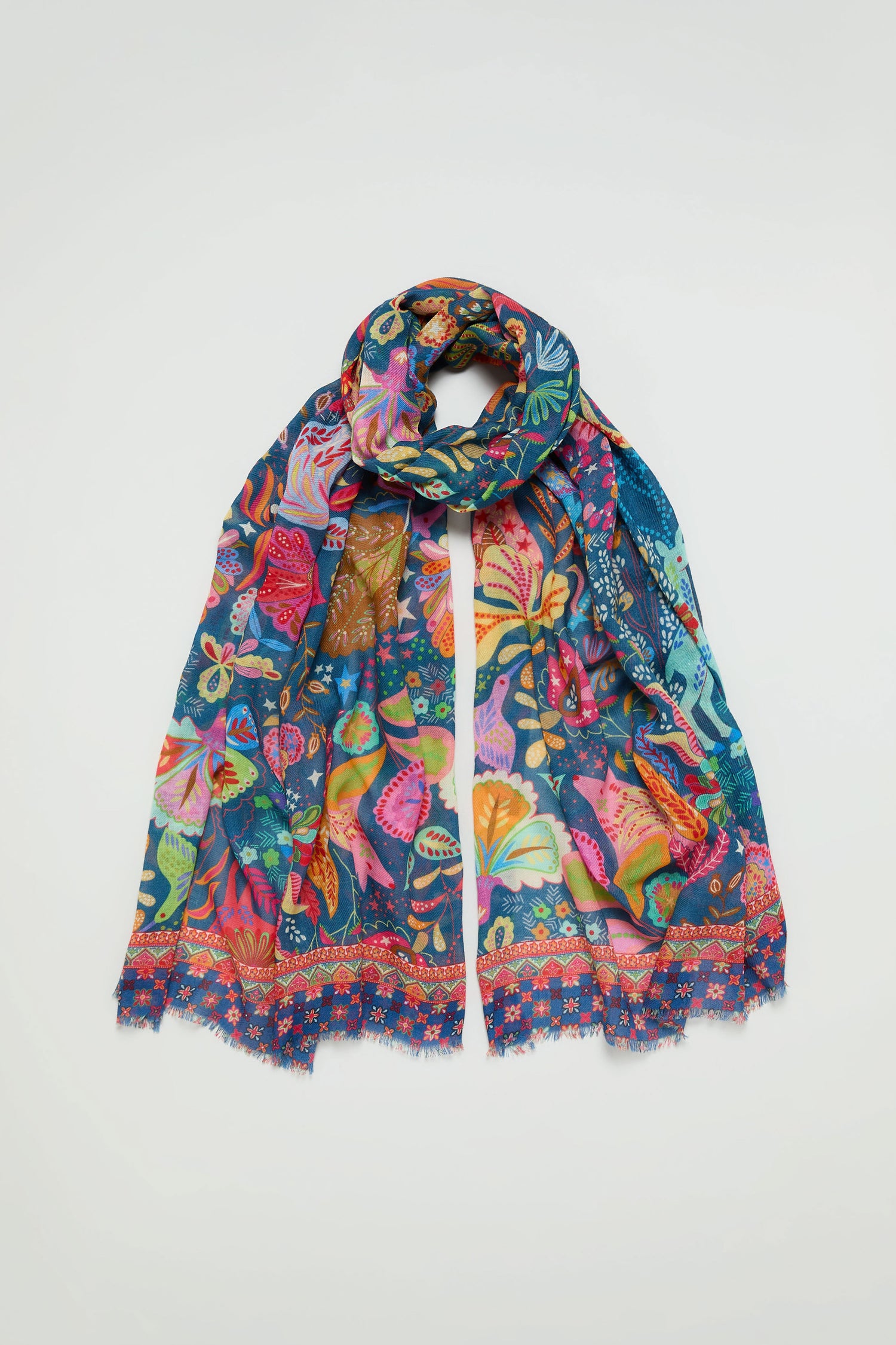 The Enchanted Woodland Wool Mix Scarf is a lightweight accessory with vibrant butterfly and botanical patterns on a blue background, finished with stylish fringed edges.