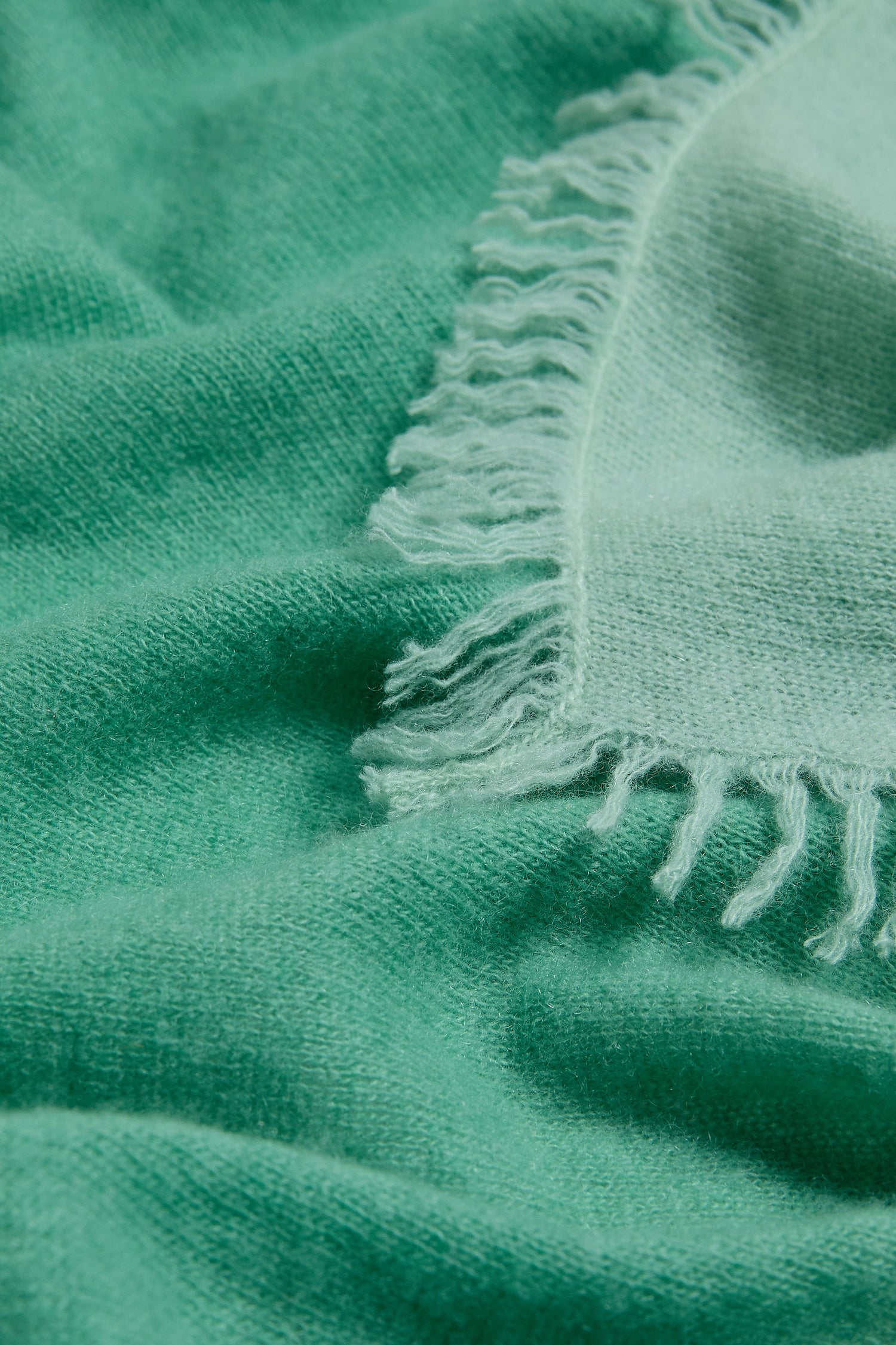 Close-up of the Ombre Cashmere Square Scarf in soft green, highlighting its fine texture, delicate fibers, and elegant fringe edge.