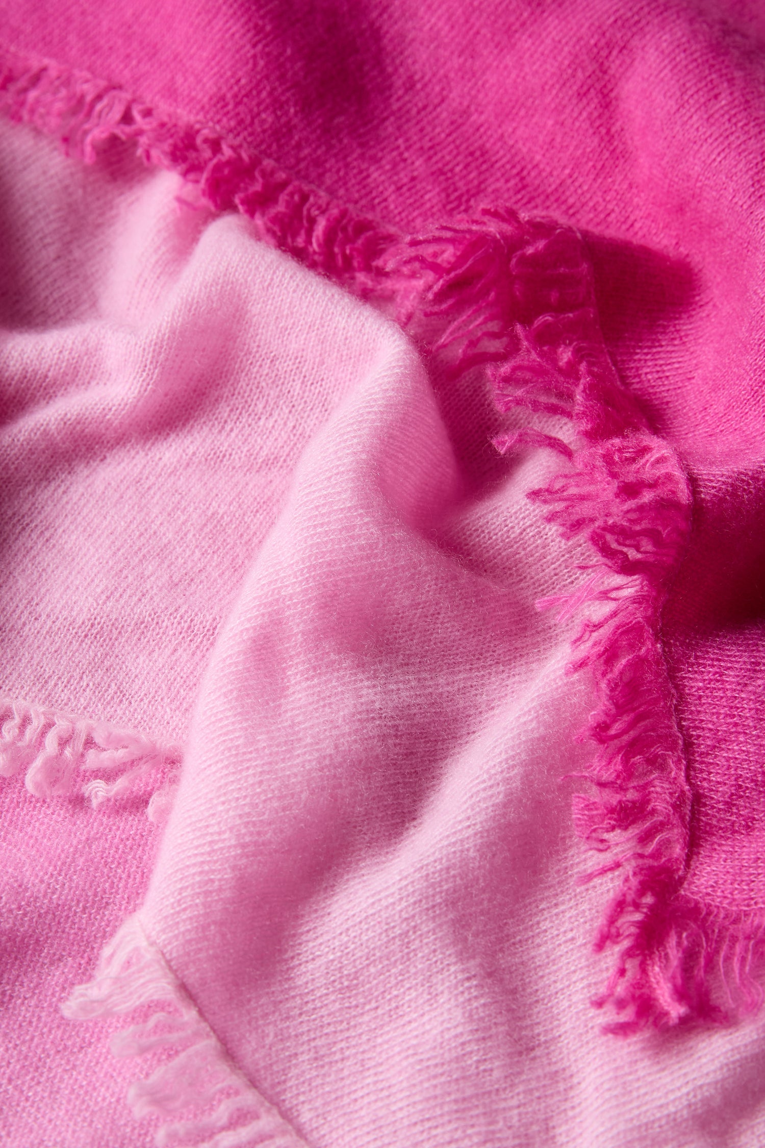 Close-up of the Ombre Cashmere Square Scarf, featuring a soft pink ombre gradient from light to dark, with fringed edges. The texture and folds enhance its luxurious appeal.