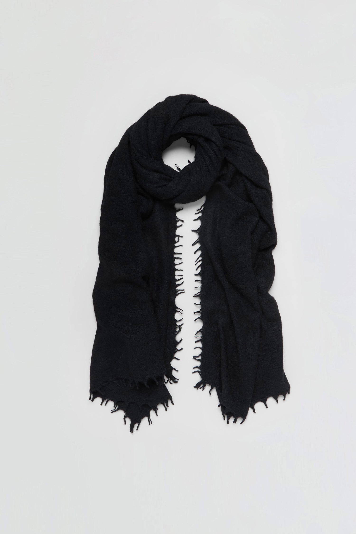 The Black Soft Cashmere Scarf, featuring frayed edges, is loosely folded and displayed against a plain white background.