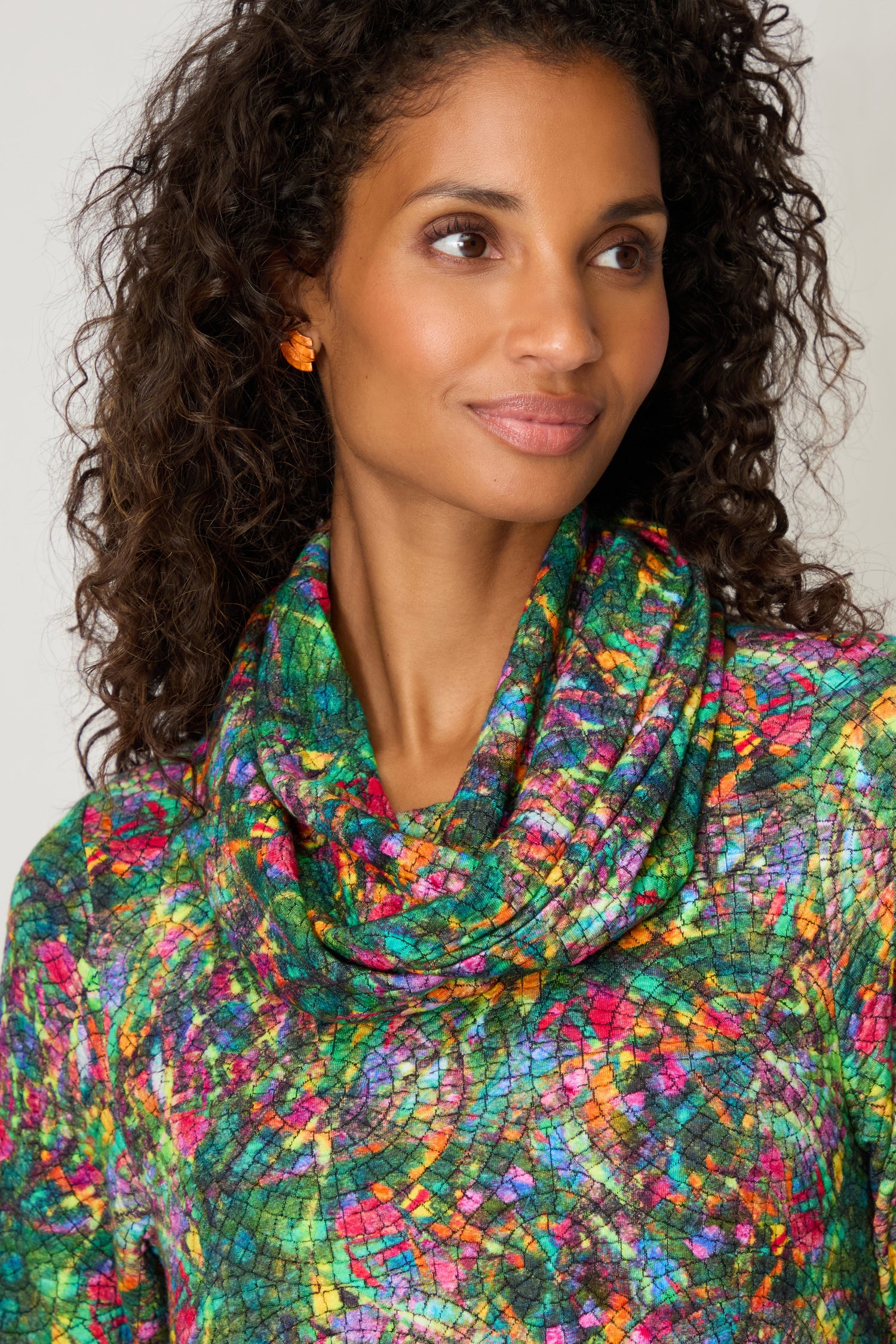 Woman with curly hair wears the Circle Textured Snood and orange earrings, looking slightly to her left against a neutral background.