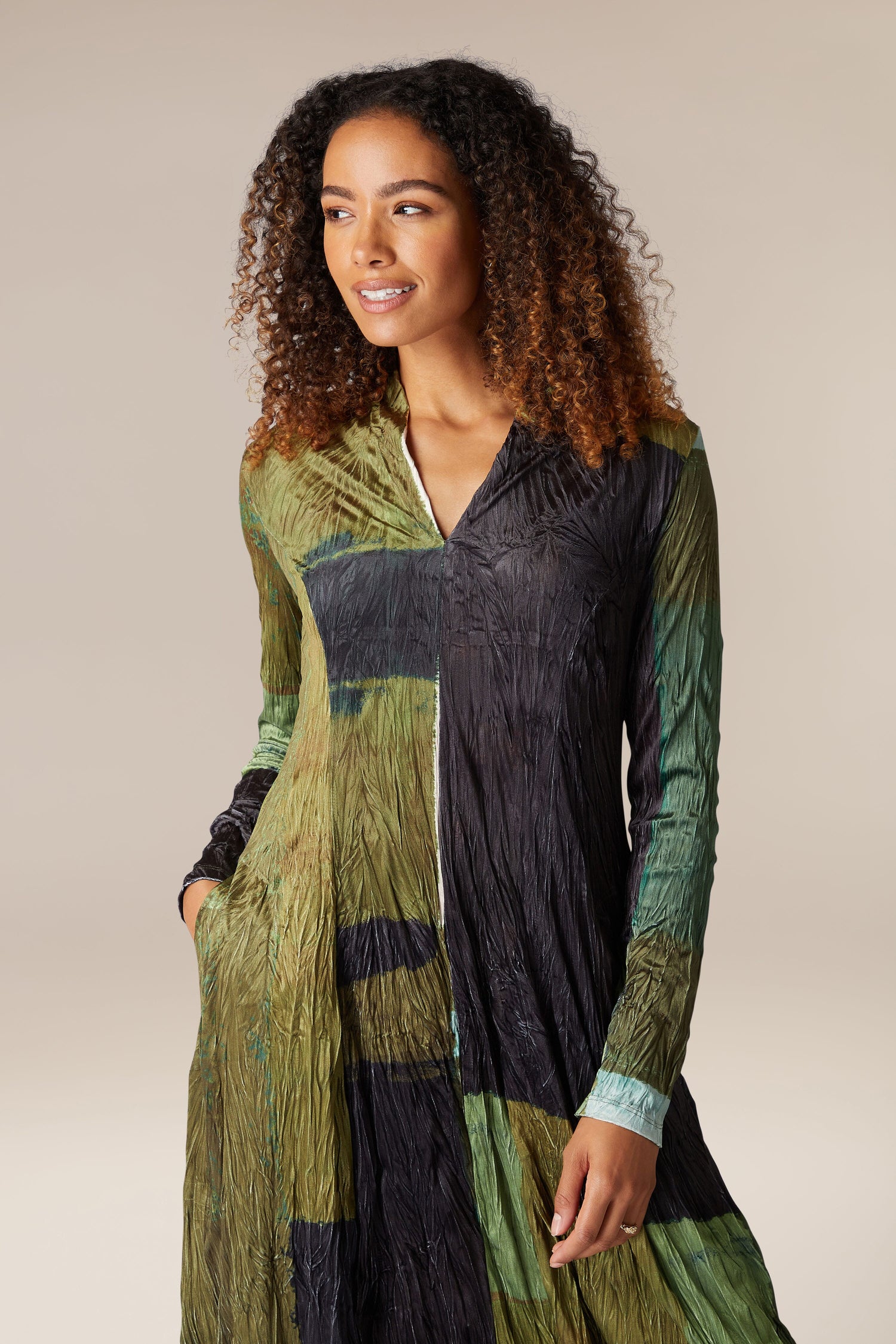 A woman wearing a long-sleeved green Block Velvet Dress.