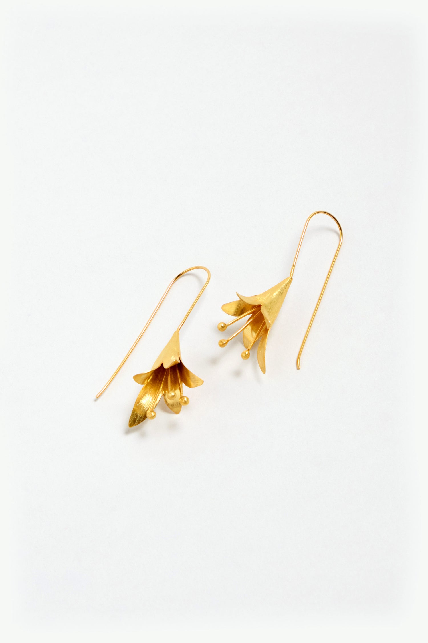 A pair of Gold Vermeil Flower Earrings with long hooks, shaped like flowers, shown on a plain white background.