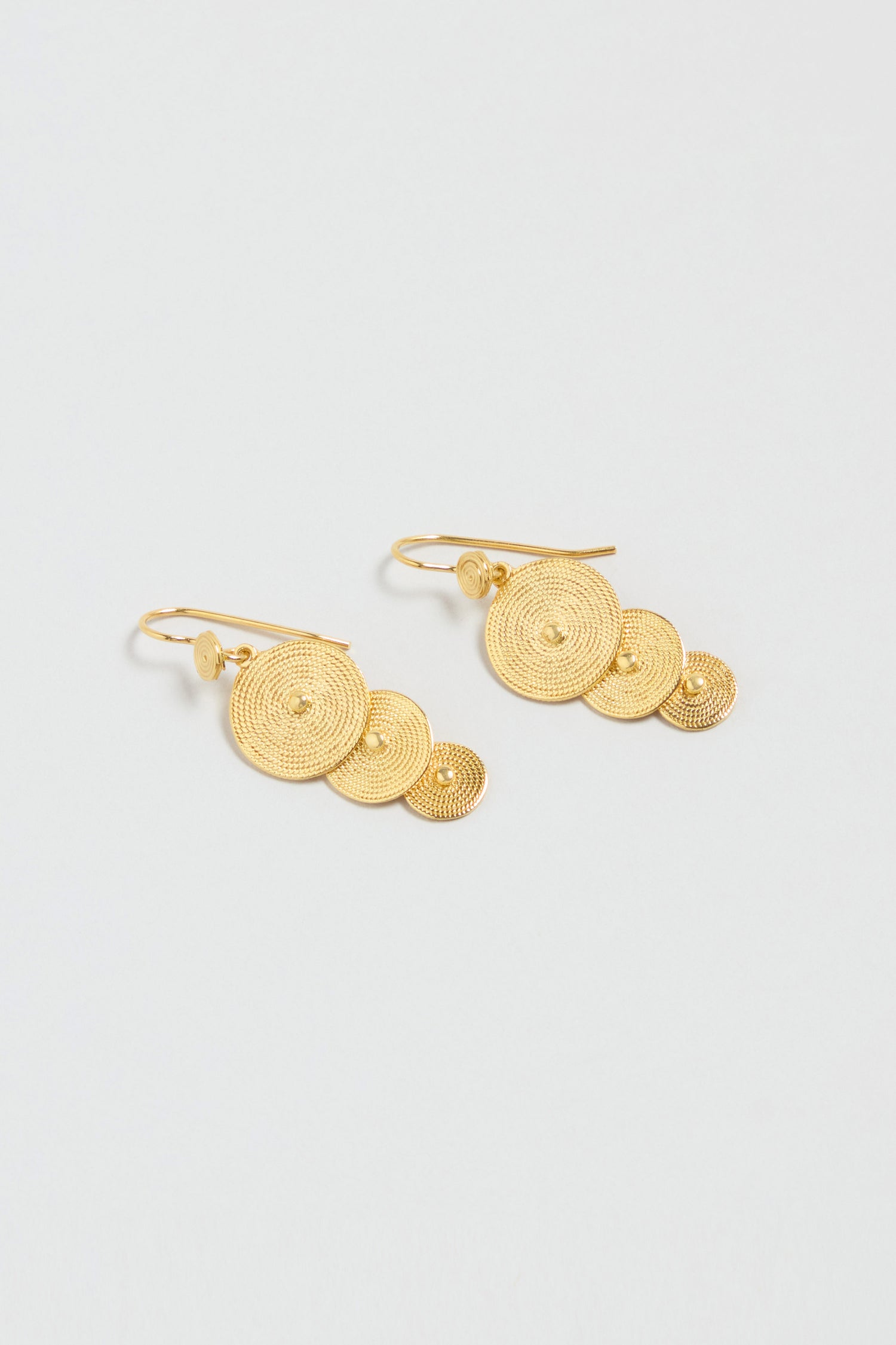 The Gold Vermeil Orbit Disc Earrings feature three textured concentric circle discs of different sizes on each earring, shown against a light background.