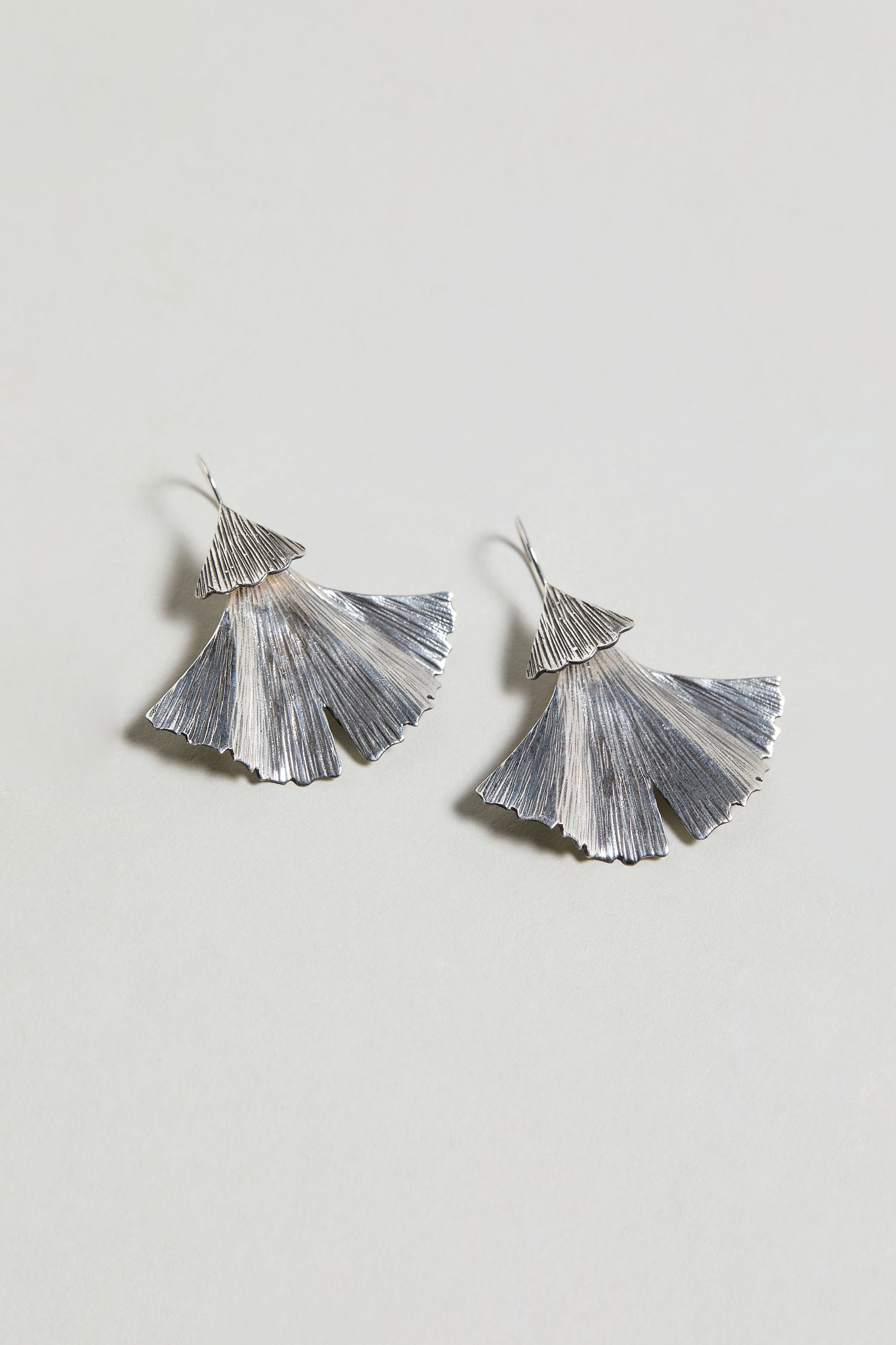 A pair of Silver Ginkgo Leaf Earrings in sterling silver with a textured design, set against a plain light background.