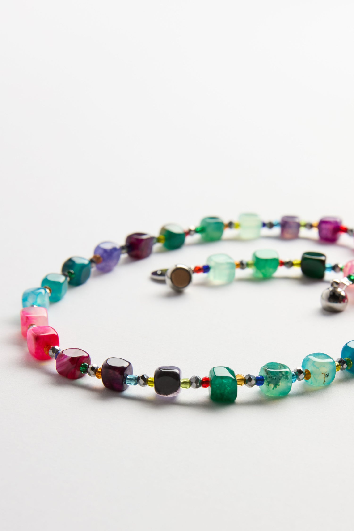 The Artisanal Rainbow Agate Cube Necklace by Arran Bay Jewellery features multicolored, irregular agate beads and a metal clasp, displayed on a white background.
