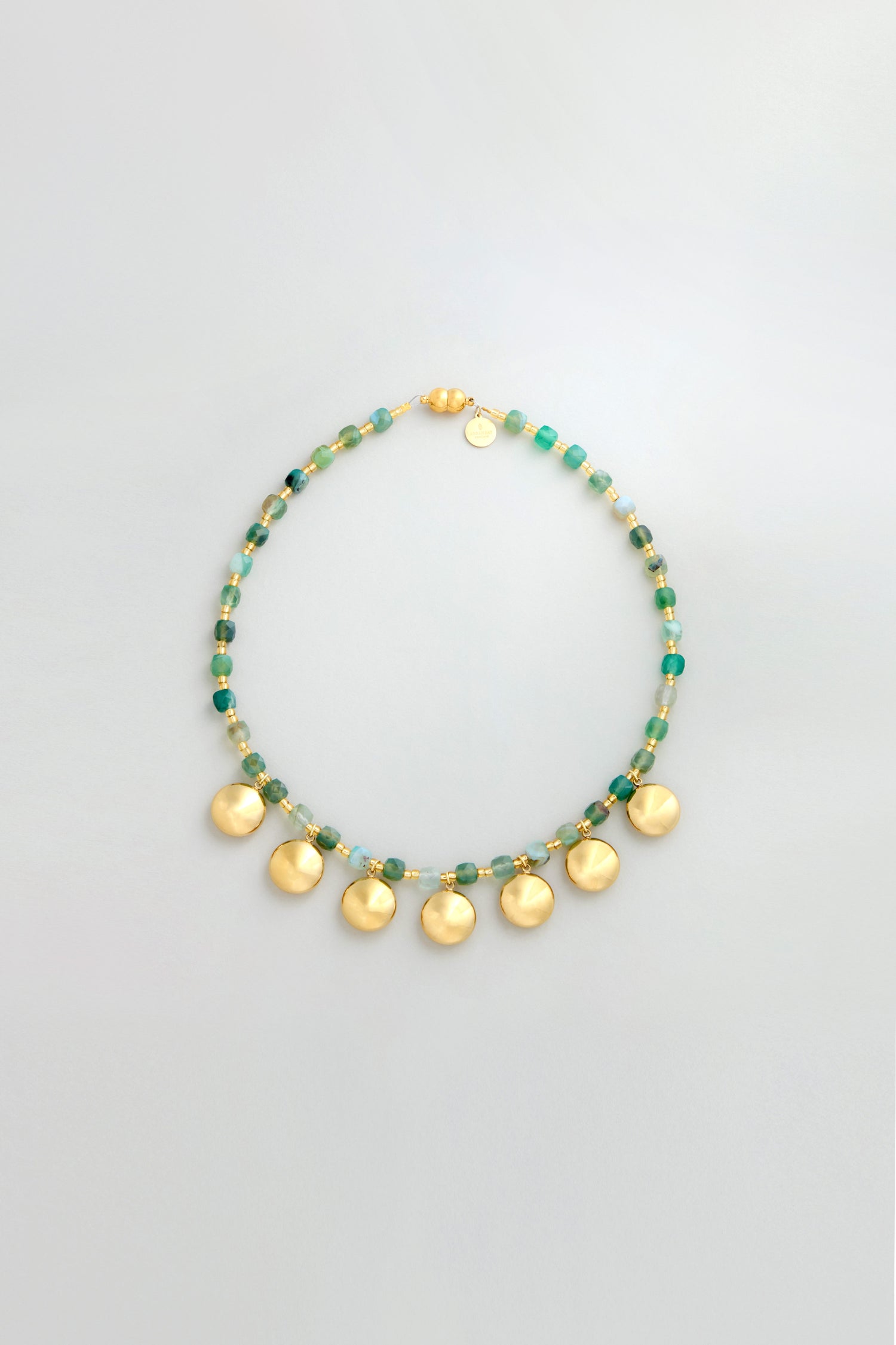 The Faceted Green Agate Charm Necklace features green agate beads, gold and green bead accents, and six round gold pendants evenly spaced for a striking charm necklace look.