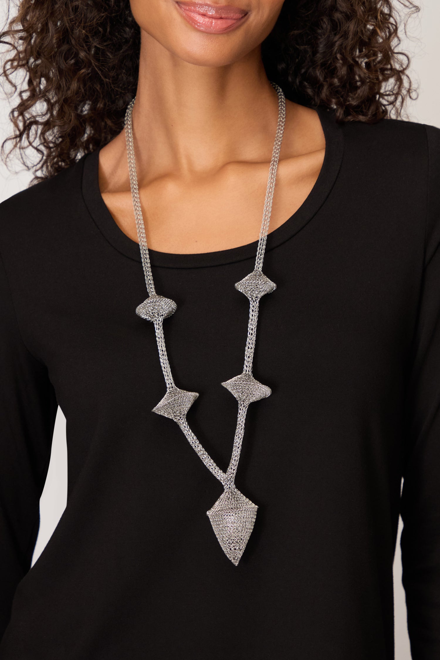 A woman wears the Hand Crocheted Snowdrop Necklace, a statement piece, over a black top.
