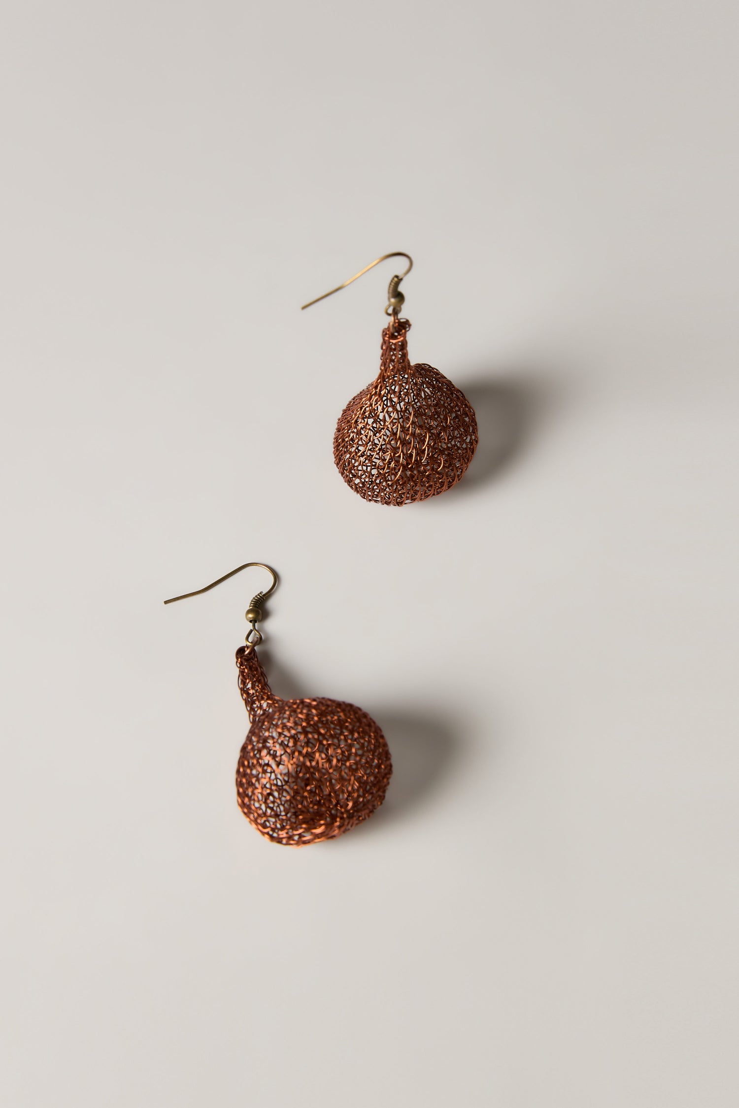 A pair of Hand Crocheted Teardrop Earrings in brown with a textured design and hook fastenings, highlighting artisanal craftsmanship, displayed on a plain light background.