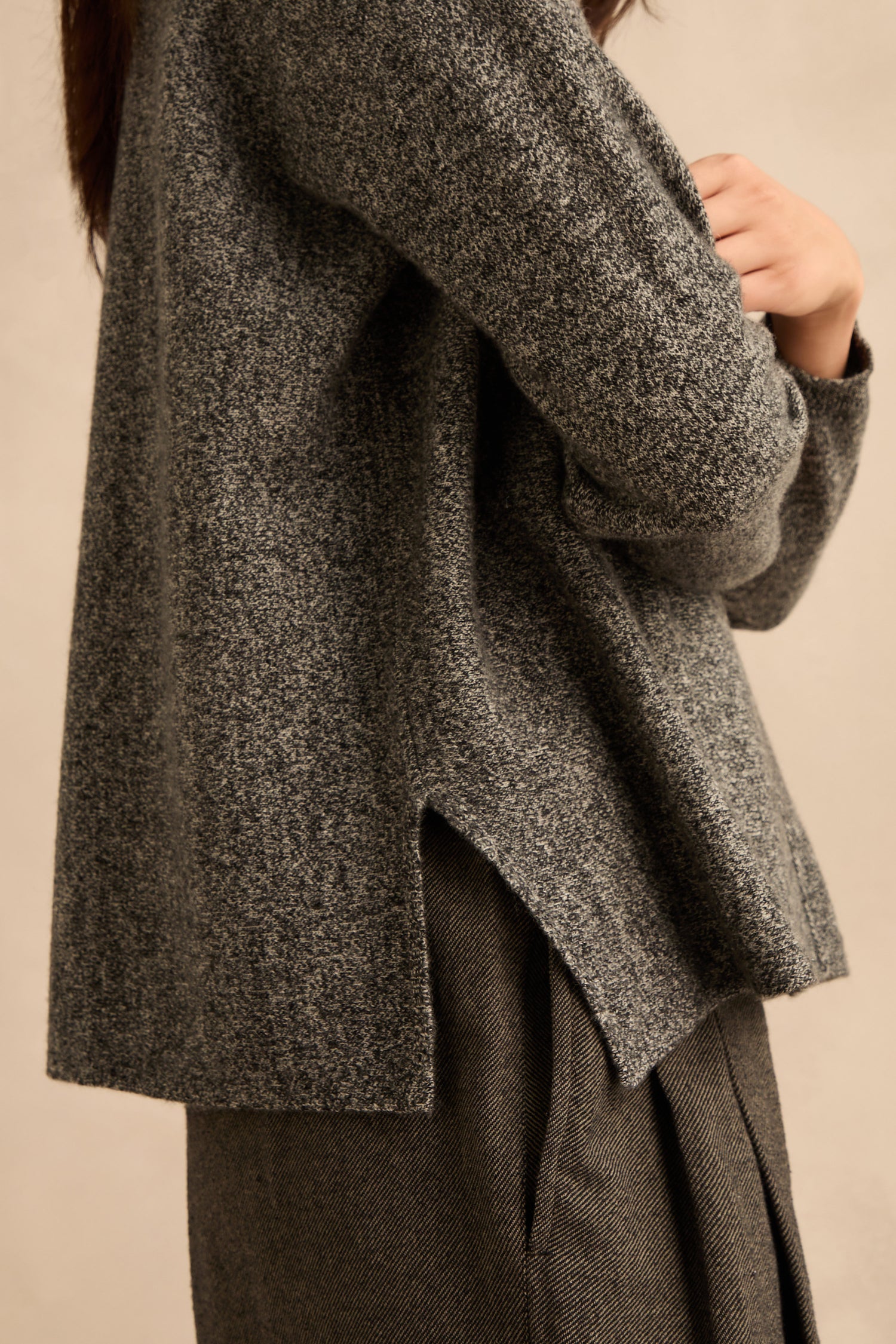 Person wearing a Black & White Merino Wool Cowl Neck Jumper with gray trousers, shown from the shoulders down against a neutral background.