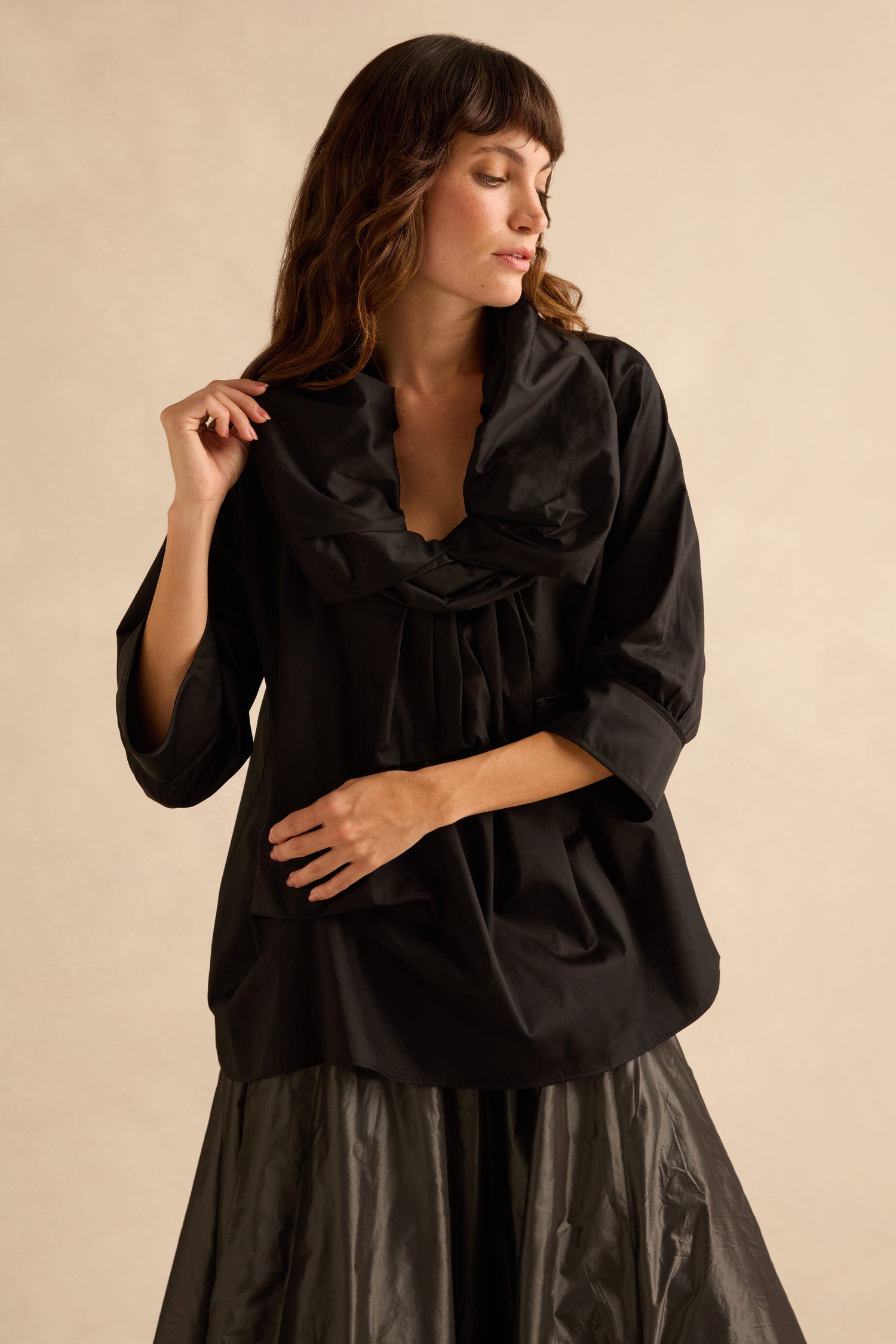 A person wearing a Black Frill Neck Easy Top, featuring a black frill neck with three-quarter length sleeves and a wide, gathered frilled collar in a relaxed silhouette.