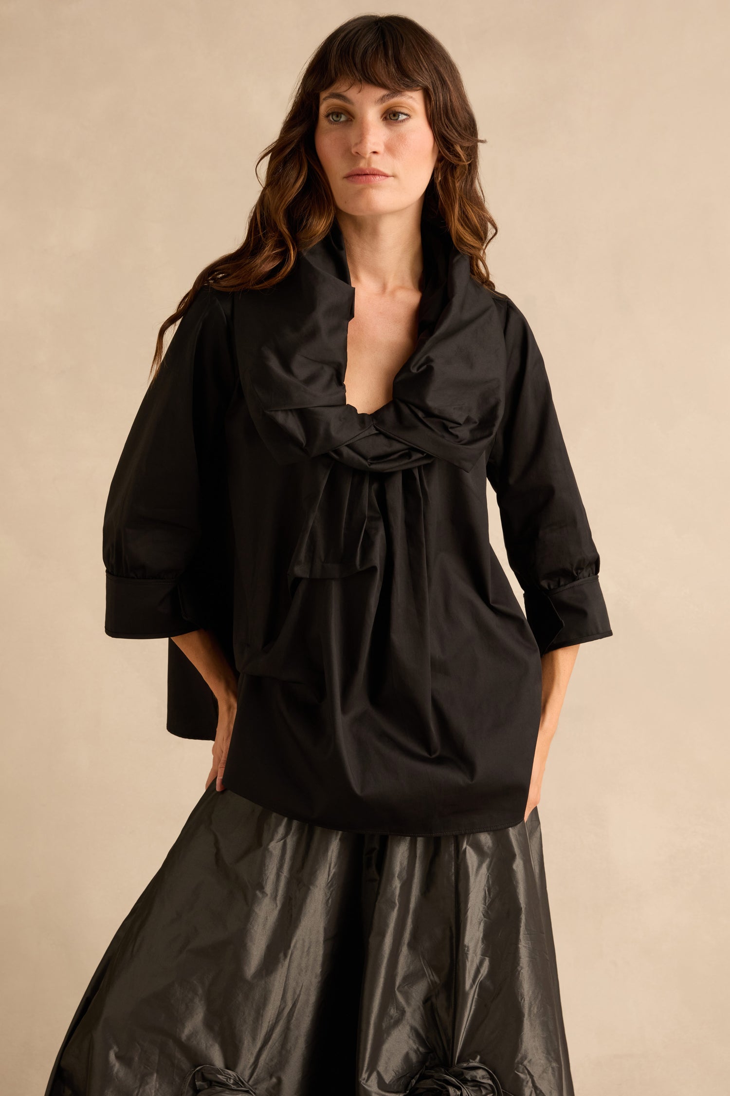 A model wears the Black Frill Neck Easy Top, a black cotton top with three-quarter length sleeves, a relaxed silhouette, and a voluminous gathered cowl neckline.