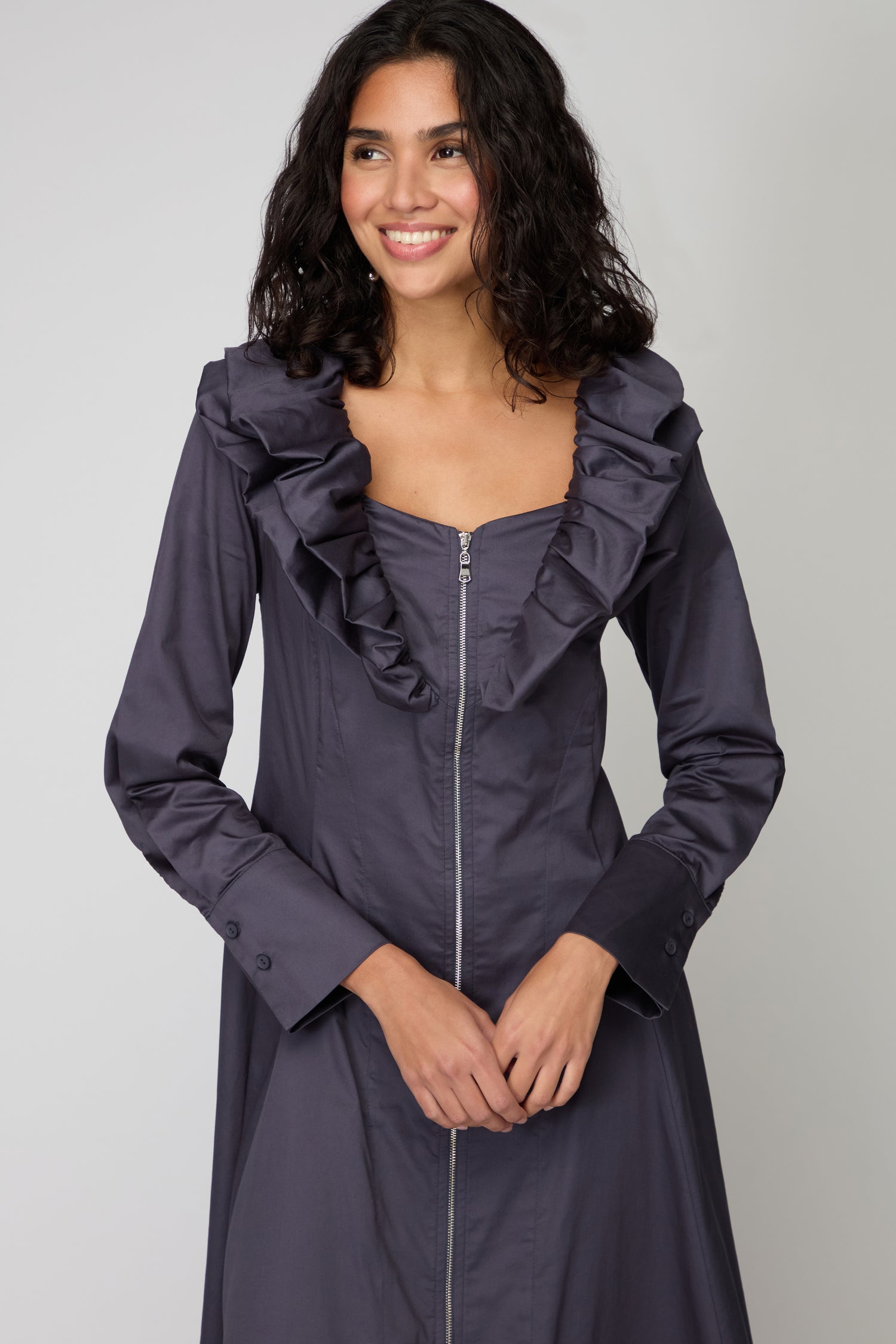 A woman smiles while wearing the Navy Frill Neck Zip Dress—an online exclusive with a ruffled neckline and long sleeves—against a plain background.