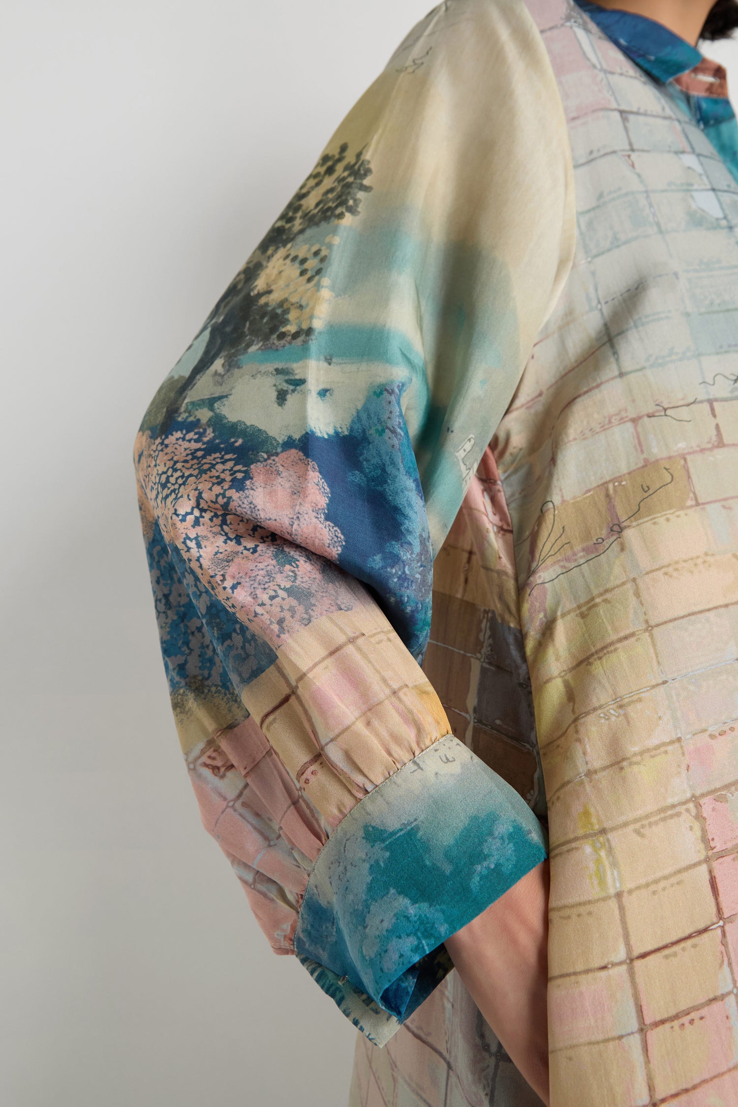A close-up of a person's bent arm wearing the Horizon Silk Shirt Dress featuring colorful abstract and grid patterns.