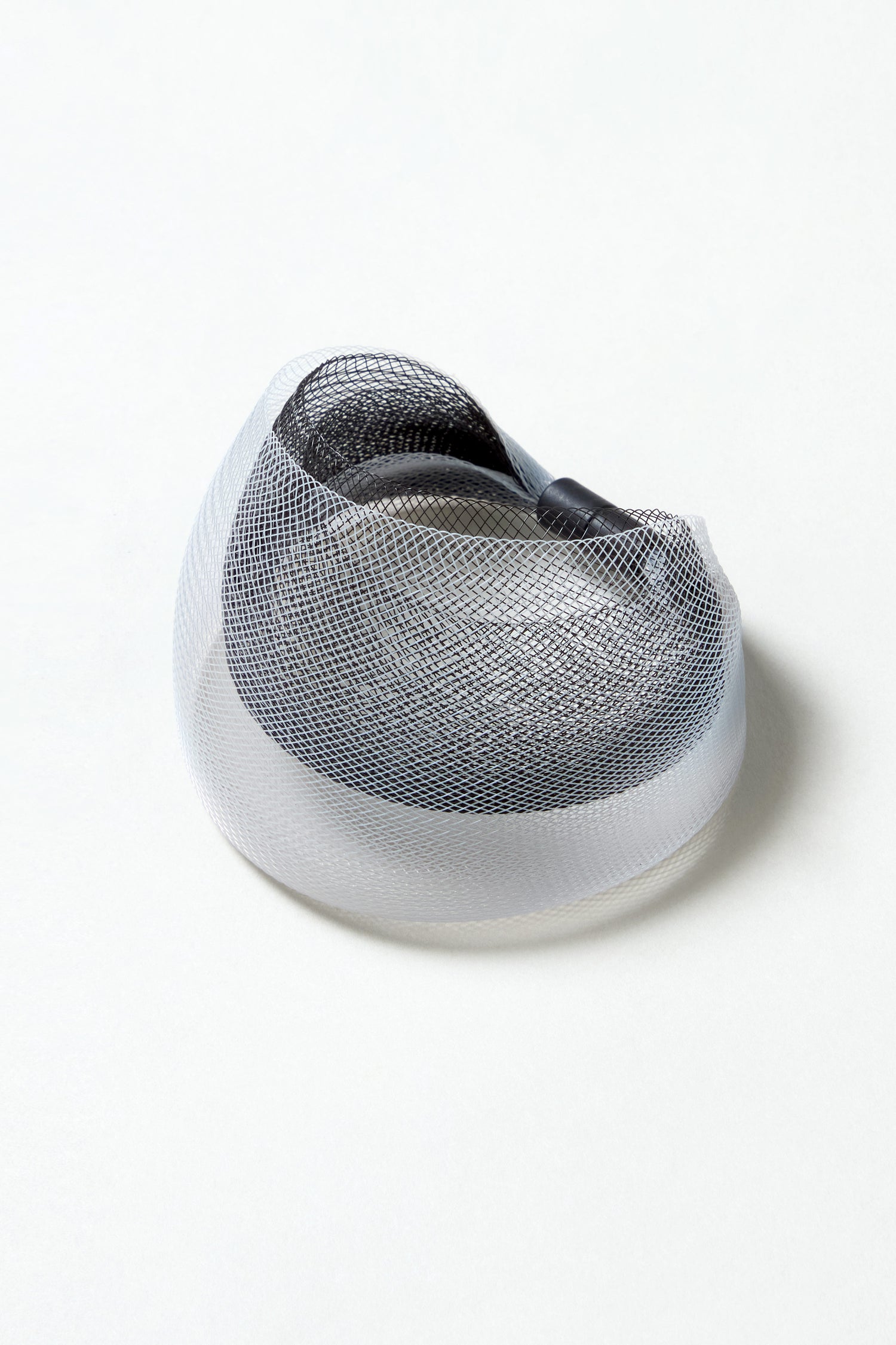 The Silver Statement Mesh Bracelet, featuring black and gray tones under a white mesh reminiscent of over-ear headphones, is displayed on a plain white background.