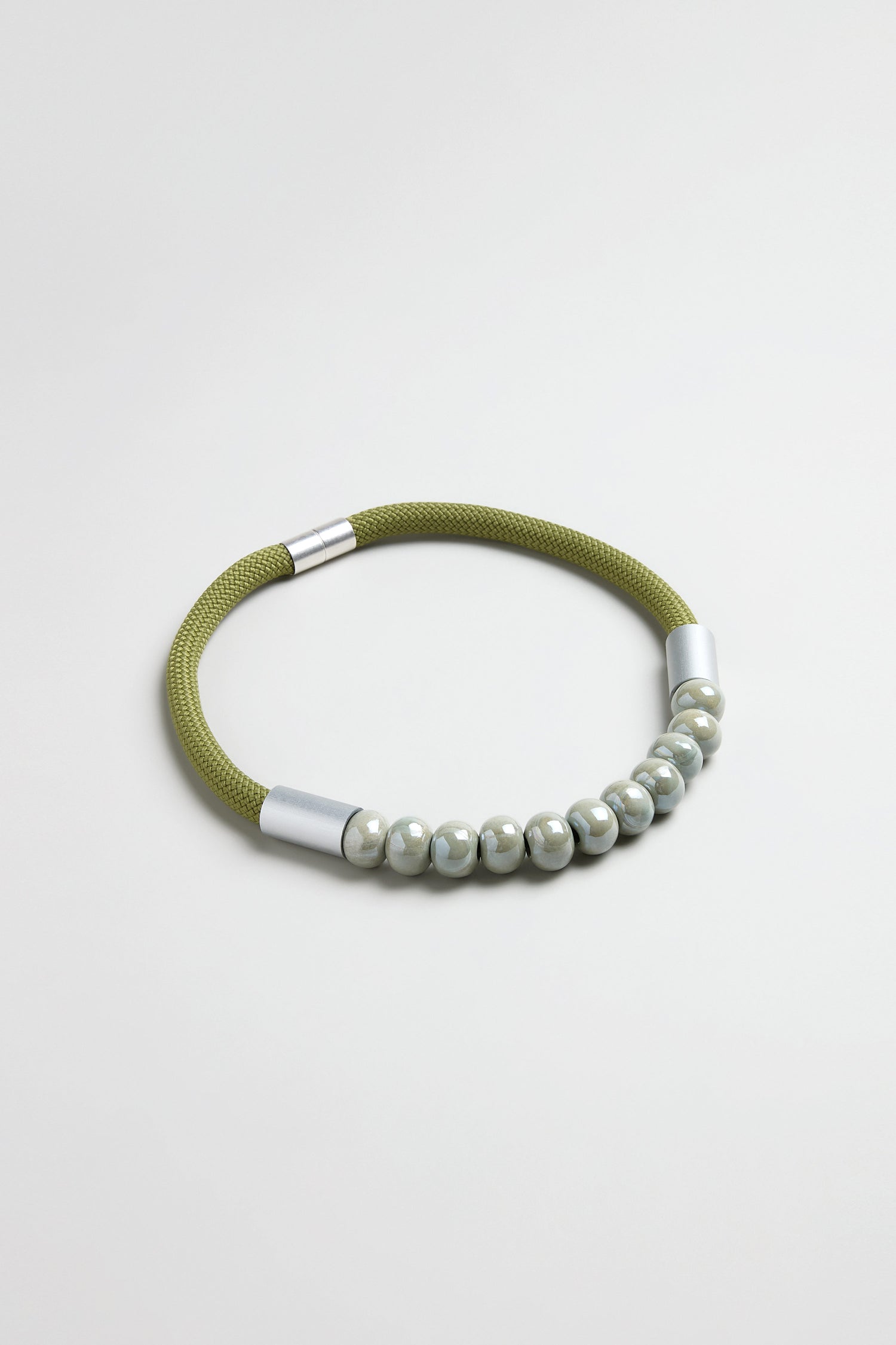 The Olive Ceramic Milkyway Necklace features glossy round beads on a green cord with silver metal ends, displayed on a plain light background.