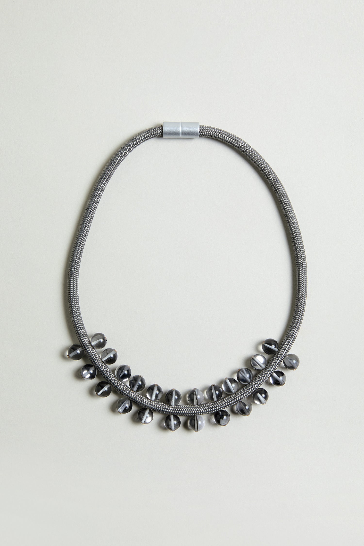 The Smoke Atmosphere Necklace features a metallic textured chain with shiny oval metal beads along the lower half. Lightweight and modern, it's ideal for everyday wear. Shown on a plain light background.