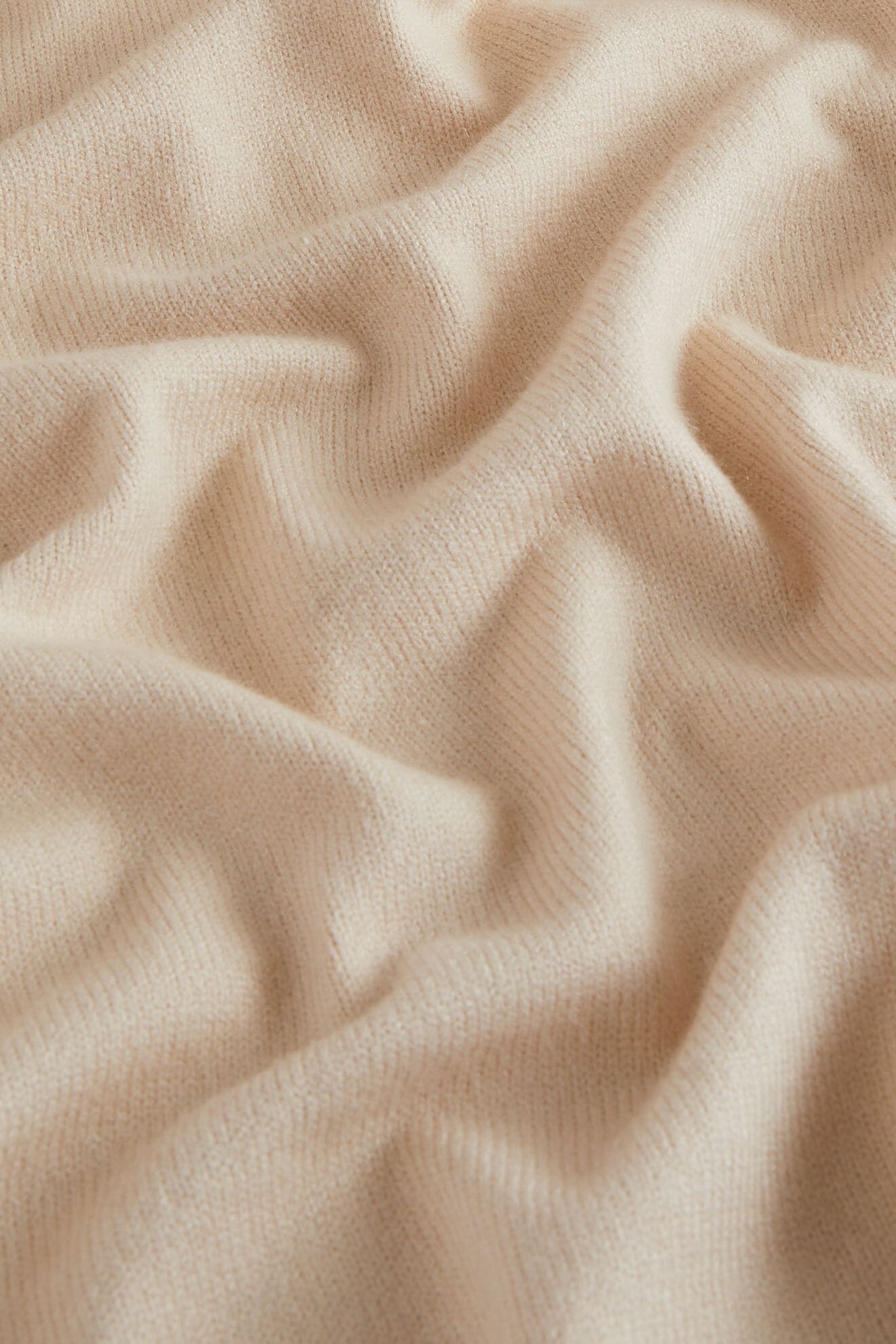 Close-up of a soft, beige, ribbed fabric with gentle folds—ideal for the Knit Scarf and perfect as a cozy winter accessory.