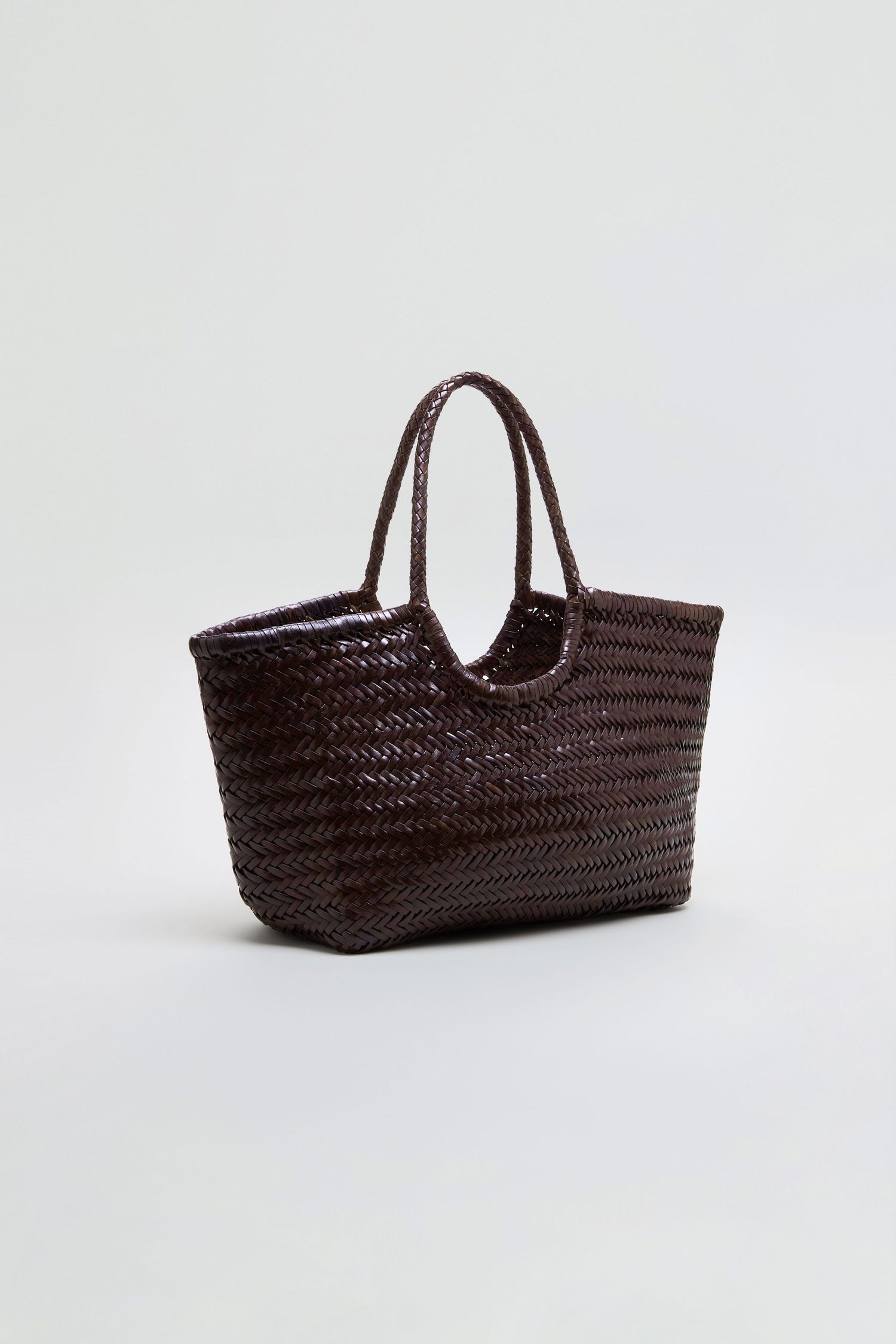 The Nantucket Woven Dark Brown Leather Bag, featuring two handles, is showcased against a plain light background, emphasizing the handwoven craftsmanship distinctive to Dragon Diffusion.
