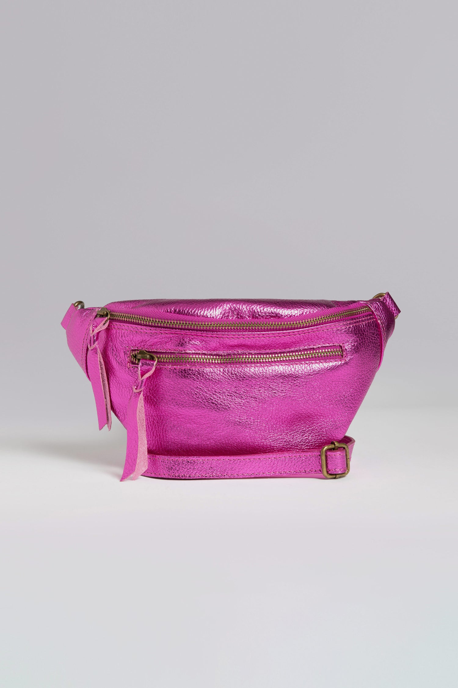 Doris Maroquinerie's Metallic Leather Crossbody Bag dazzles with its iridescent finish, featuring a front zipper pocket and an adjustable strap against a plain gray backdrop.