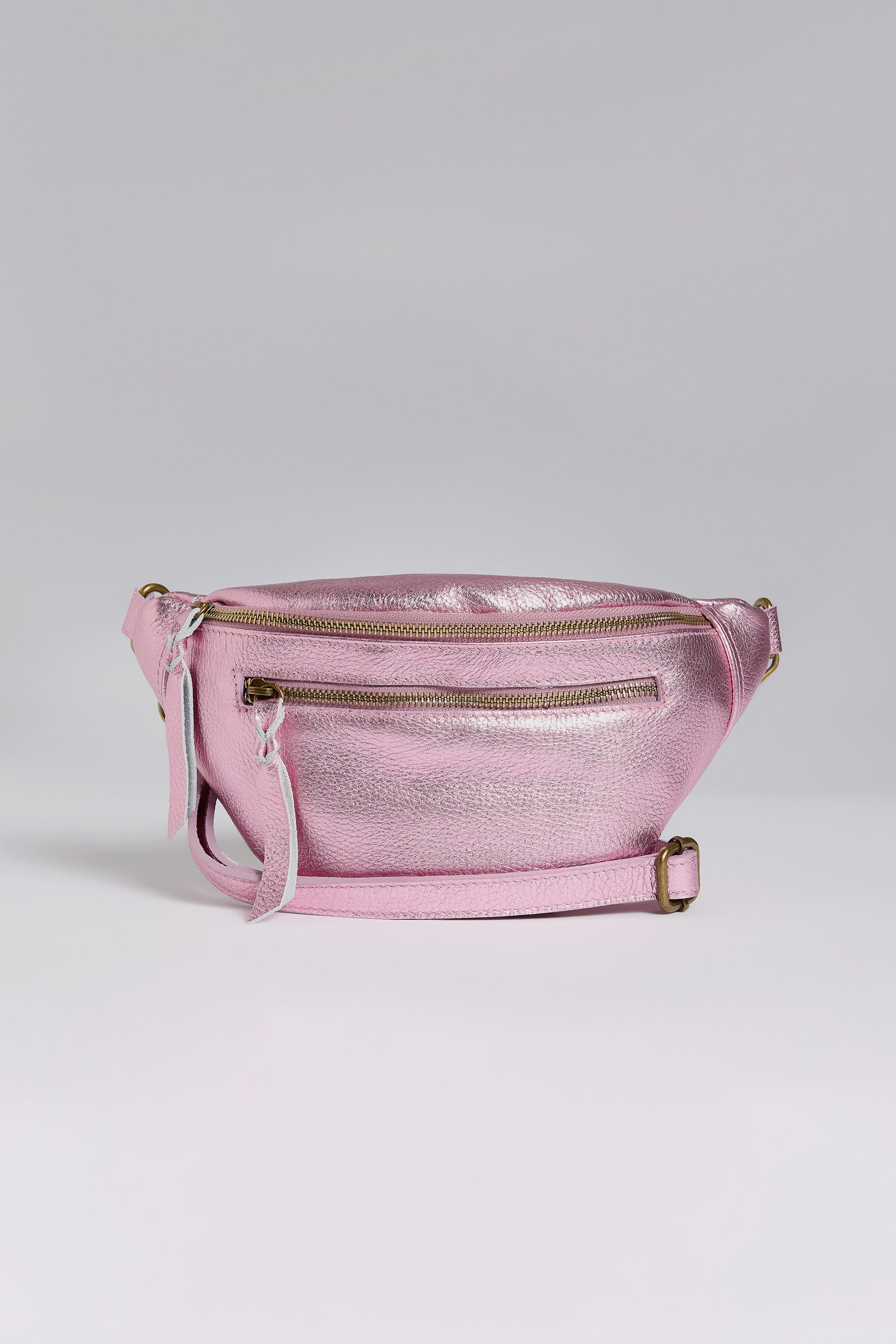 Explore Doris Maroquinerie's newest creation: the Metallic Leather Crossbody Bag, presented in shiny pink iridescent leather. It boasts a main zippered compartment, front zippered pocket, and adjustable strap for a blend of style and functionality.
