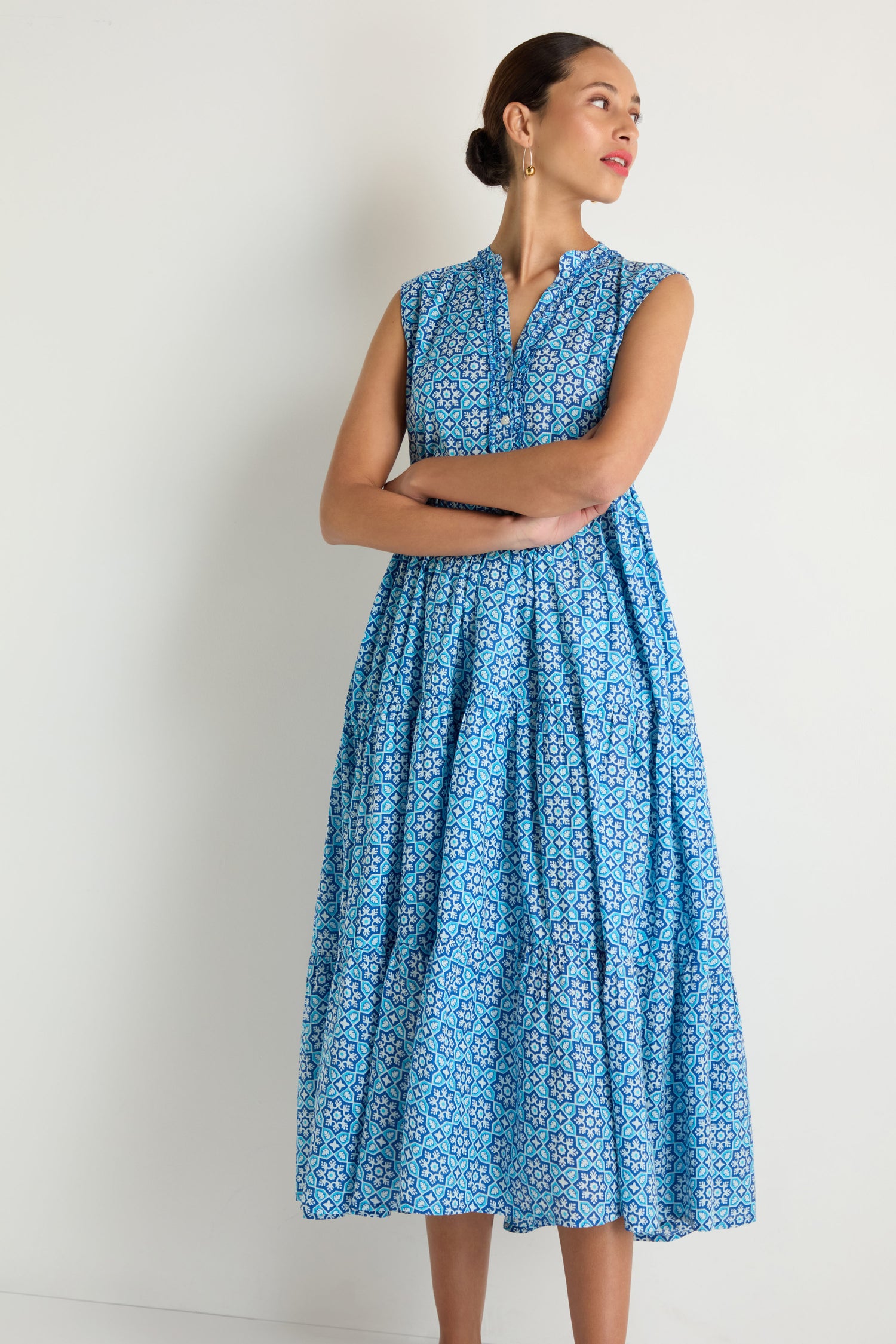 A woman wearing the Floral Tiered Dress stands against a plain white background with her arms crossed, looking to the side.