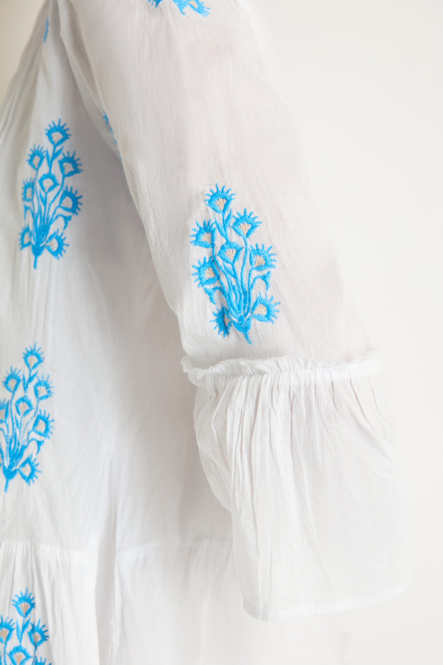 Close-up of the Embroidered Floral Flared Sleeve Tunic, crafted from pure cotton with blue and yellow floral embroidery on lightweight fabric and stylish long flared sleeves.